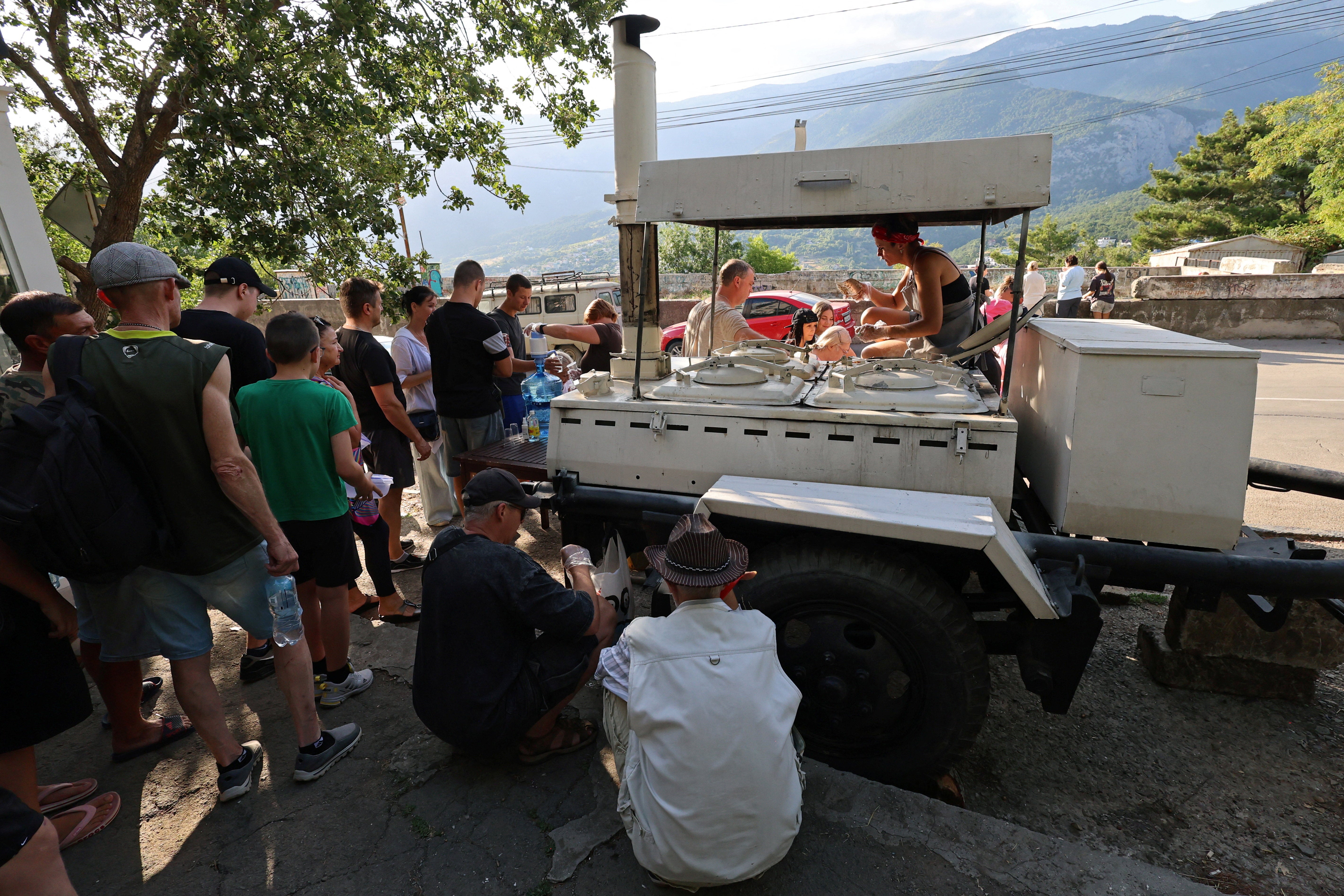 People line up for hot meals at a field kitchen set up by the local authorities in the settlement of Massandra, Crimea (Reuters)