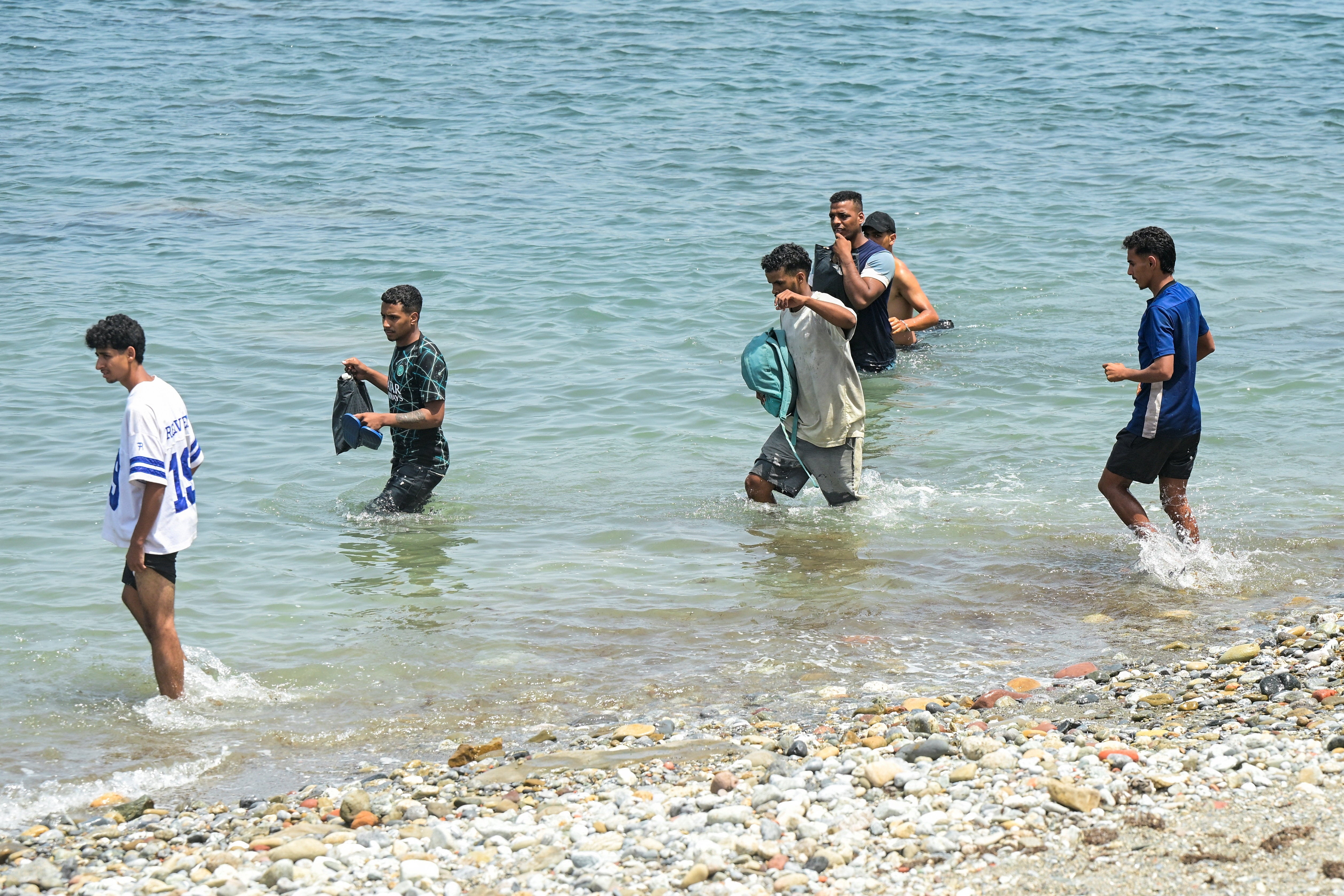 Migrants waddle in water, as they attempt to make their way past a group of Spanish soldiers (Reuters)