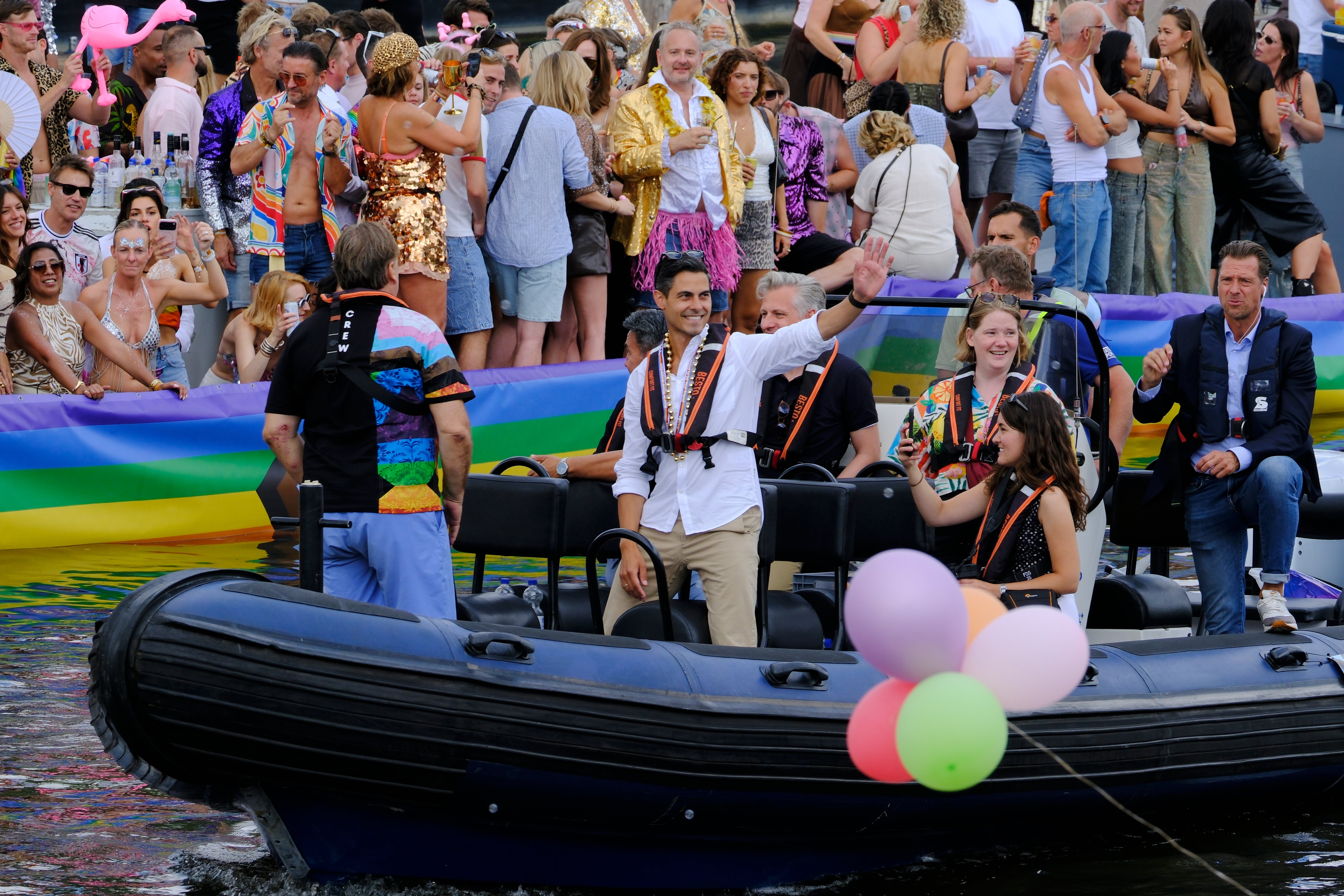 Openly gay Dutch Prime Minister Rob Jetten, dressed in a white shirt, black life vest and gold necklace, waved to crowds as he sailed in a small boat through the colorfully decorated parade of 80 vessels