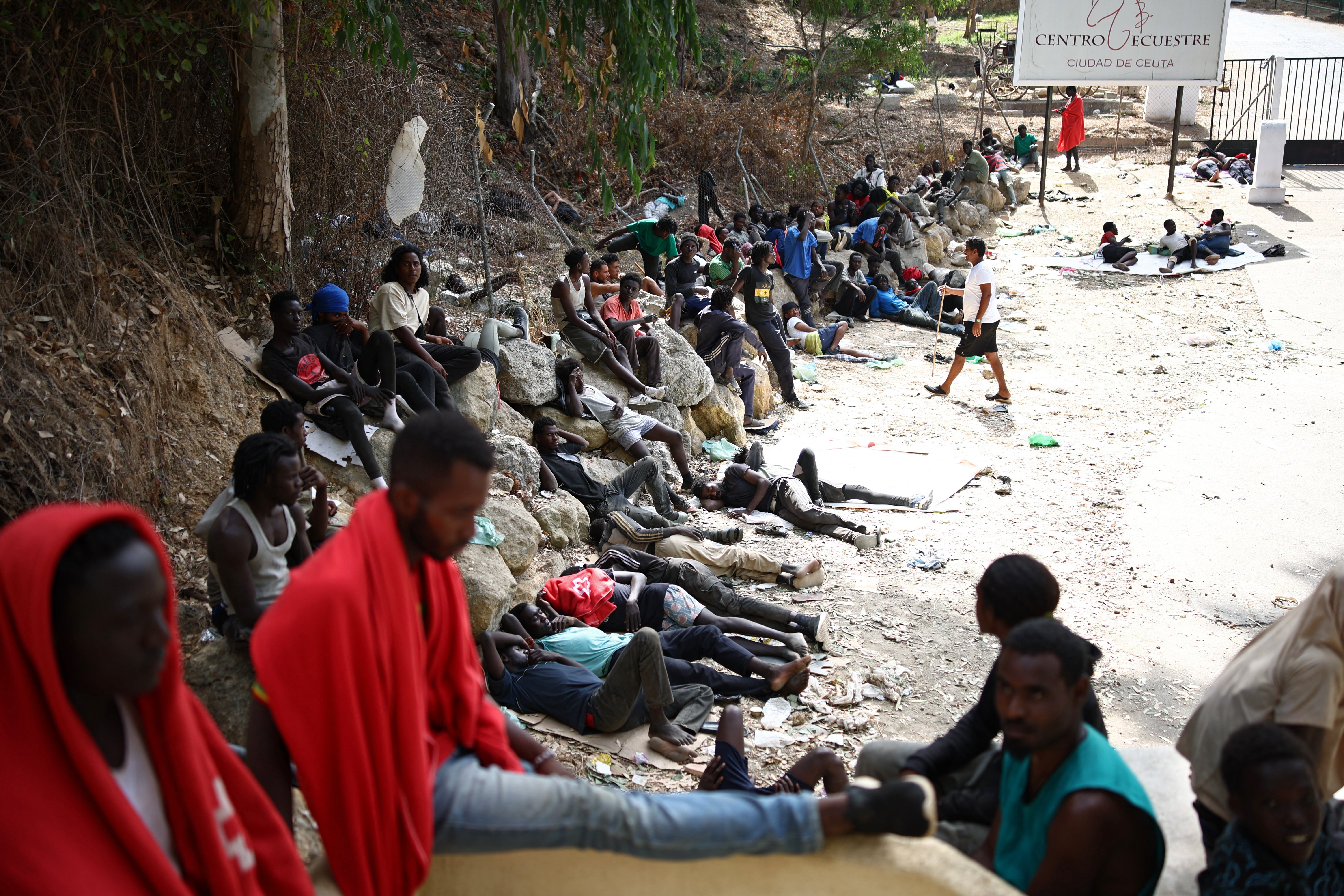 Migrants sit outside the CETI short-stay migrant centre in the Spanish north African exclave of Ceuta on 1 August