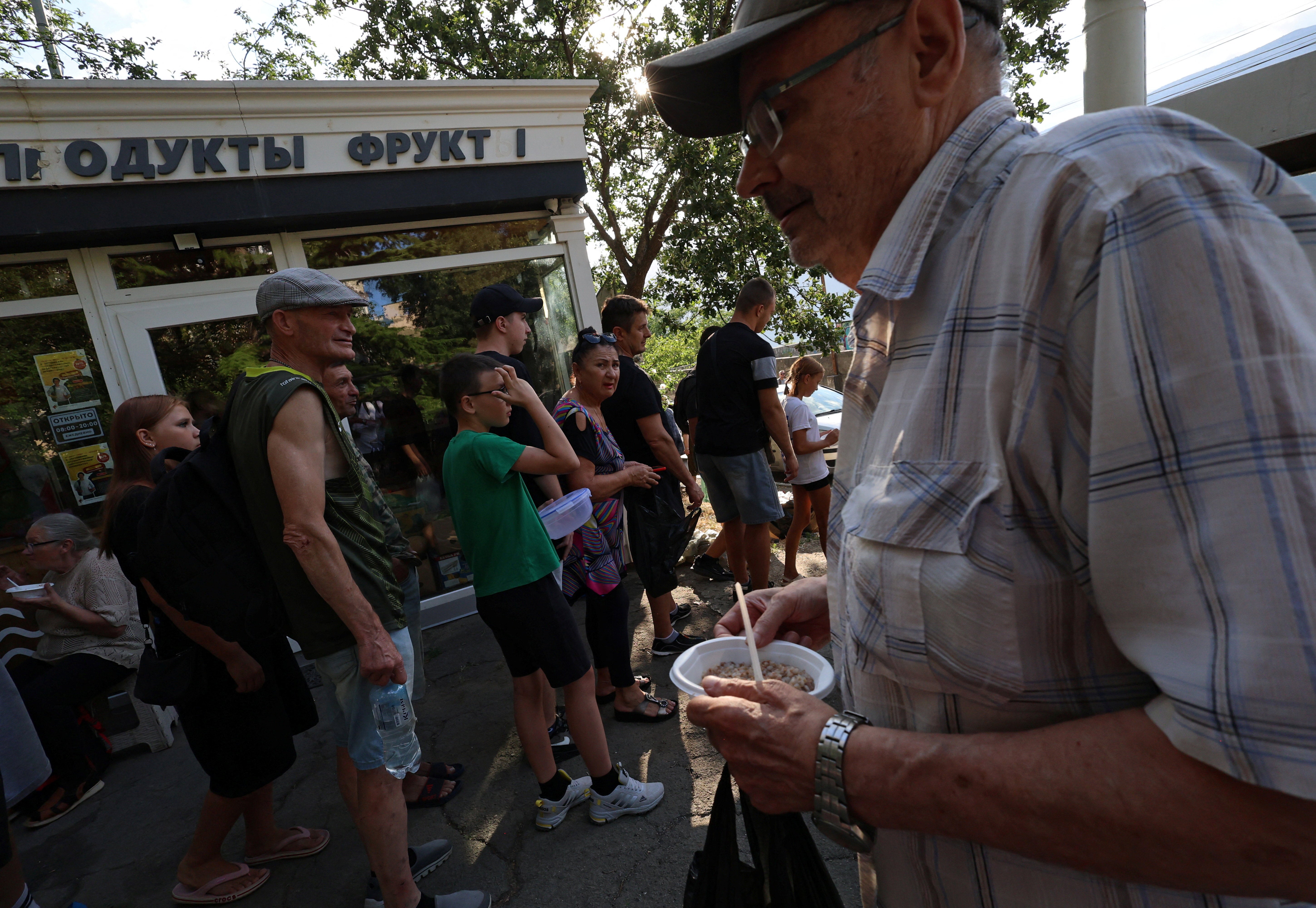 People line up for hot meals at a field kitchen set up by the local authorities in the settlement of Massandra (Reuters)