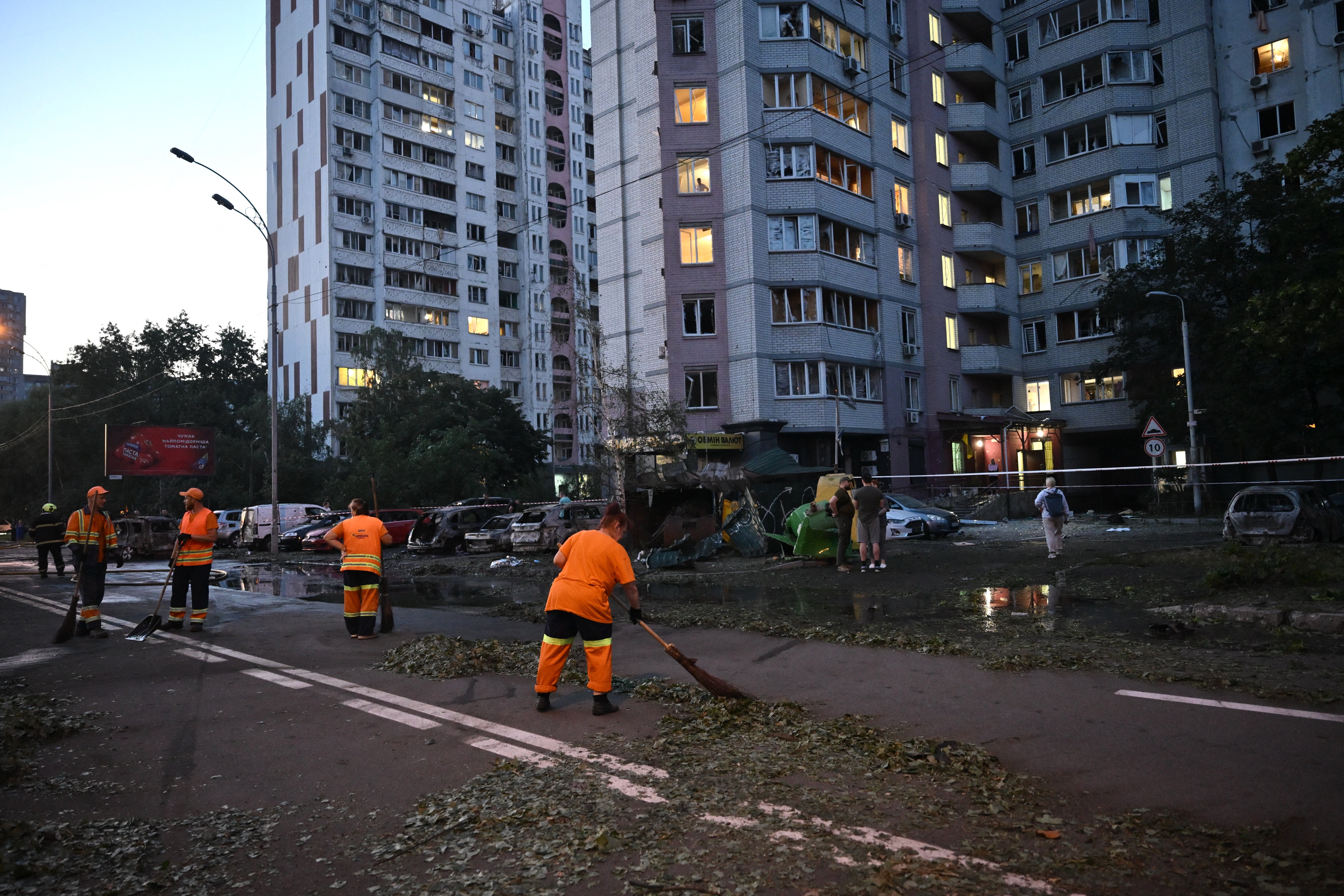Communal workers clear trash outside a multi-storey residential building damaged following massive Russian ballistic missile strikes in the Ukrainian capital of Kyiv