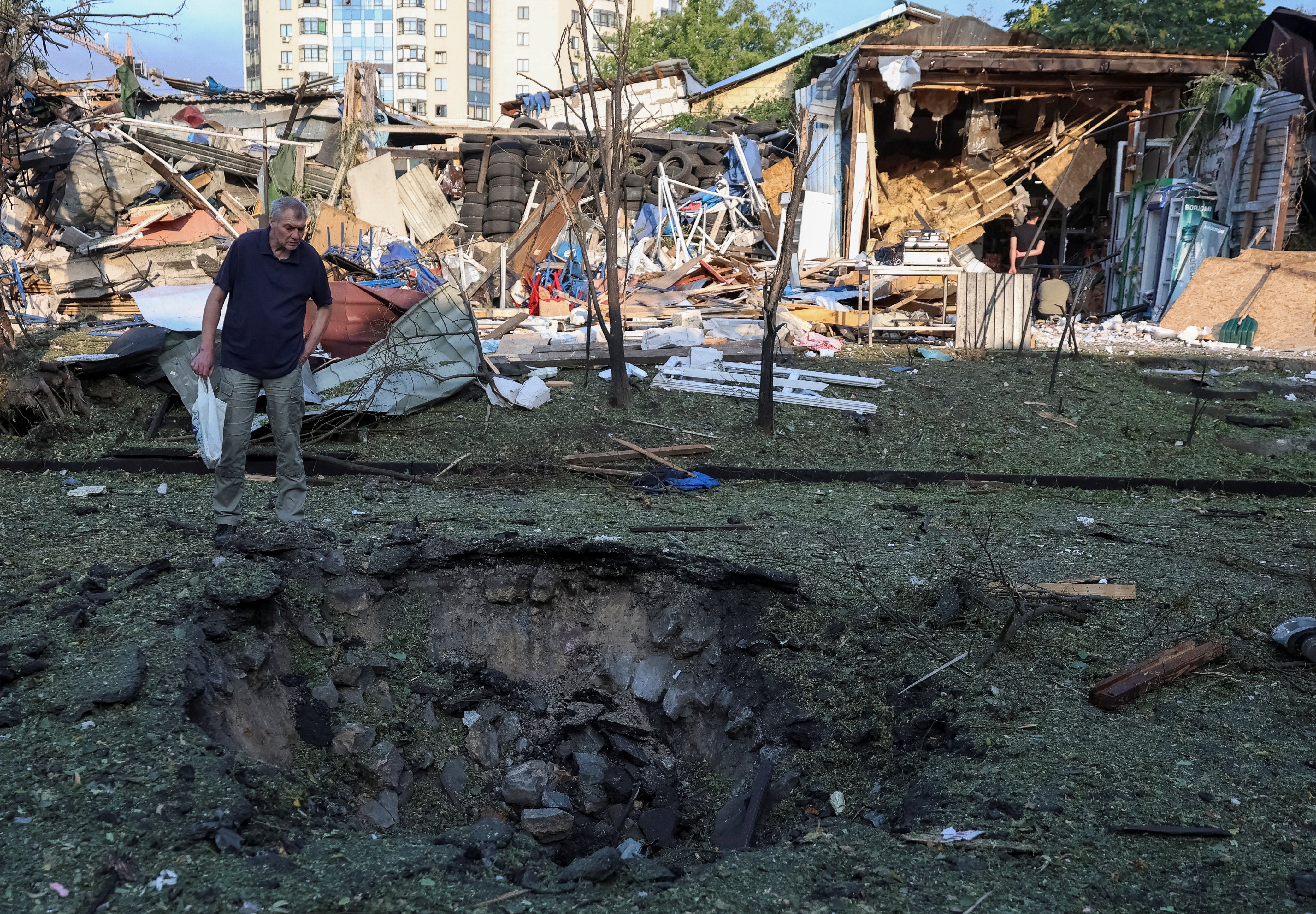 A resident looks at a crater at a site of a Russian missile strike, amid Russia's attack on Ukraine, in Kyiv region, Ukraine