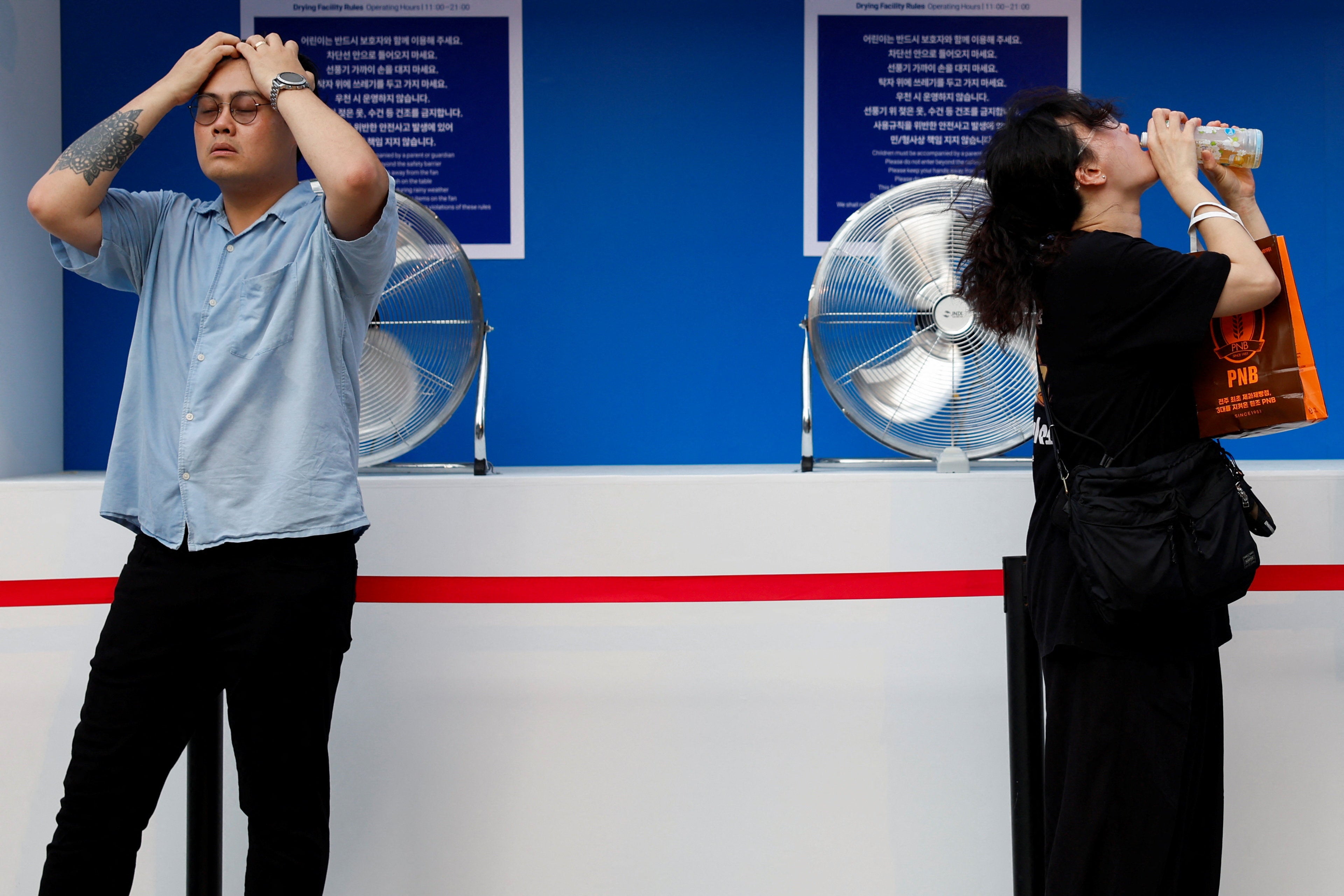 People cool off in front of fans during a heatwave in Seoul, South Korea