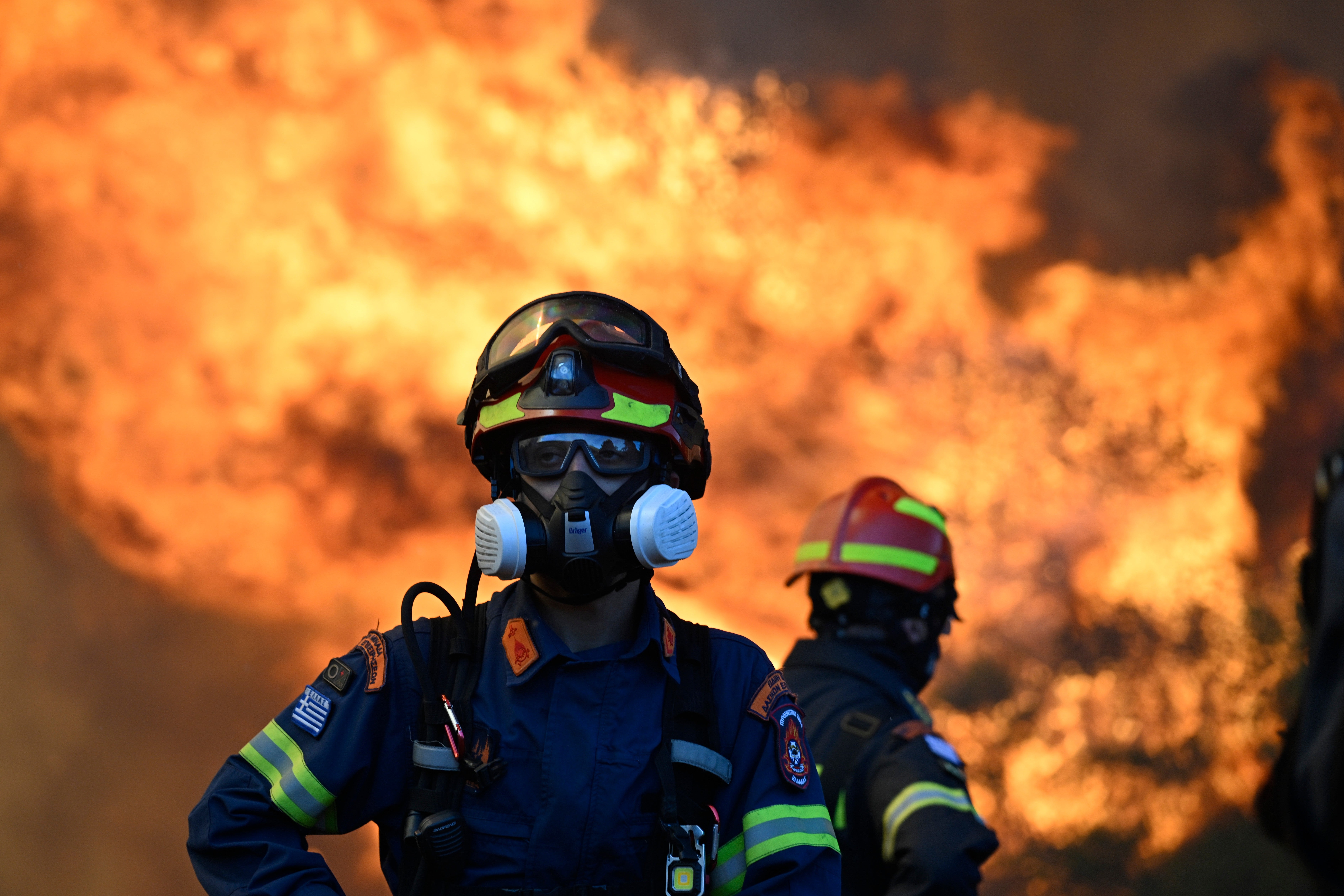 A firefighter stands as flames rising during a wildfire near Porto Germeno