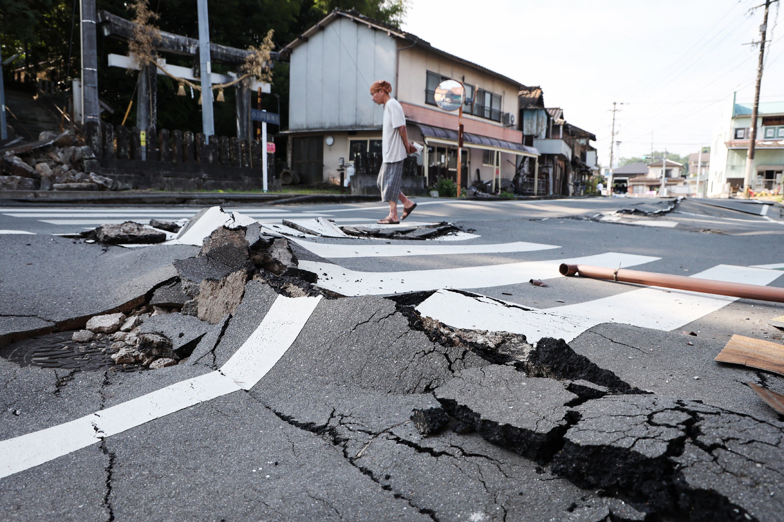 Un hombre camina por una carretera destruida en Uki, prefectura de Kumamoto.