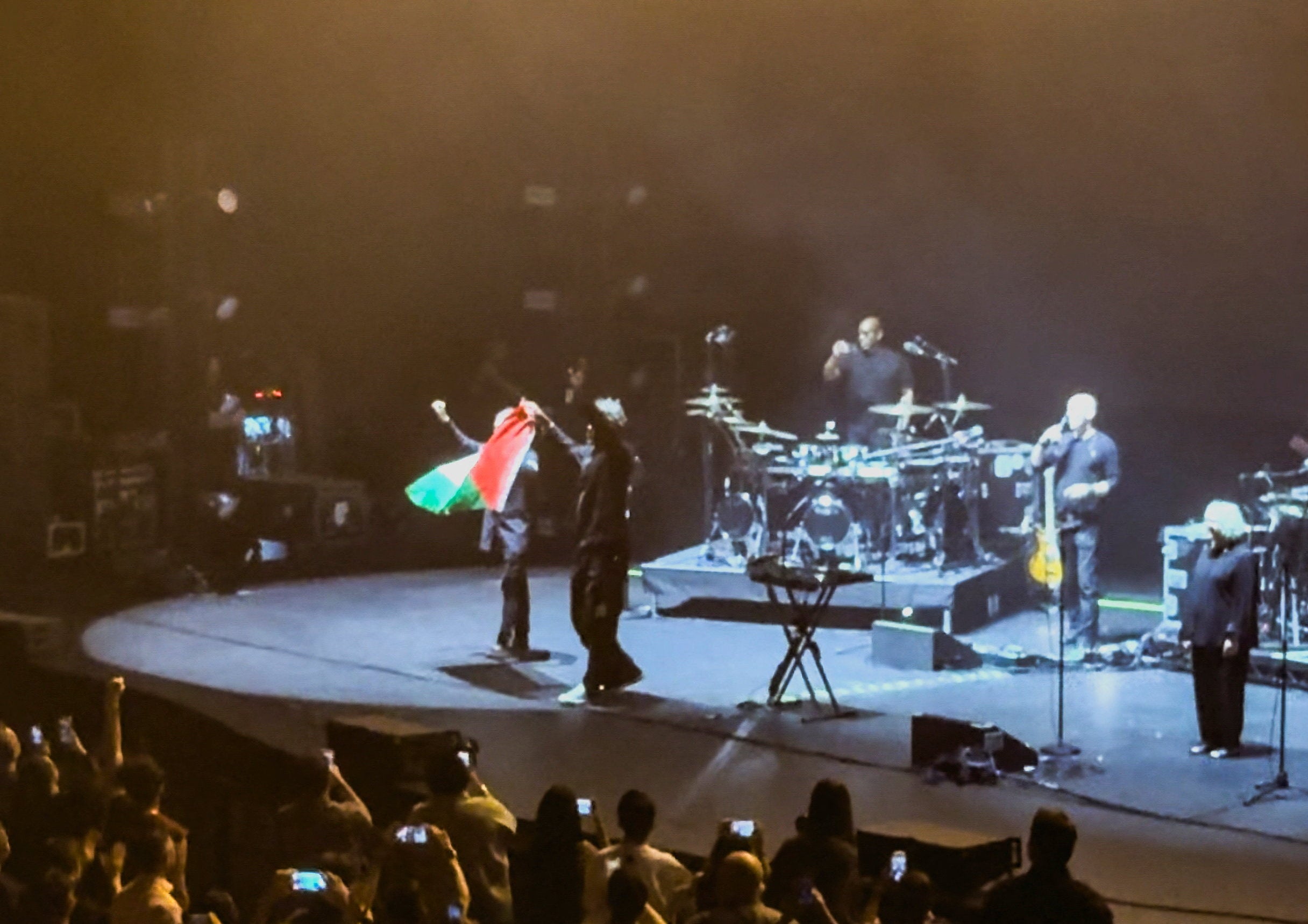 Robert Del Naja and Grant Marshall from Massive Attack stand with a Palestinian flag onstage at the end of their performance in Singapore (Reuters)