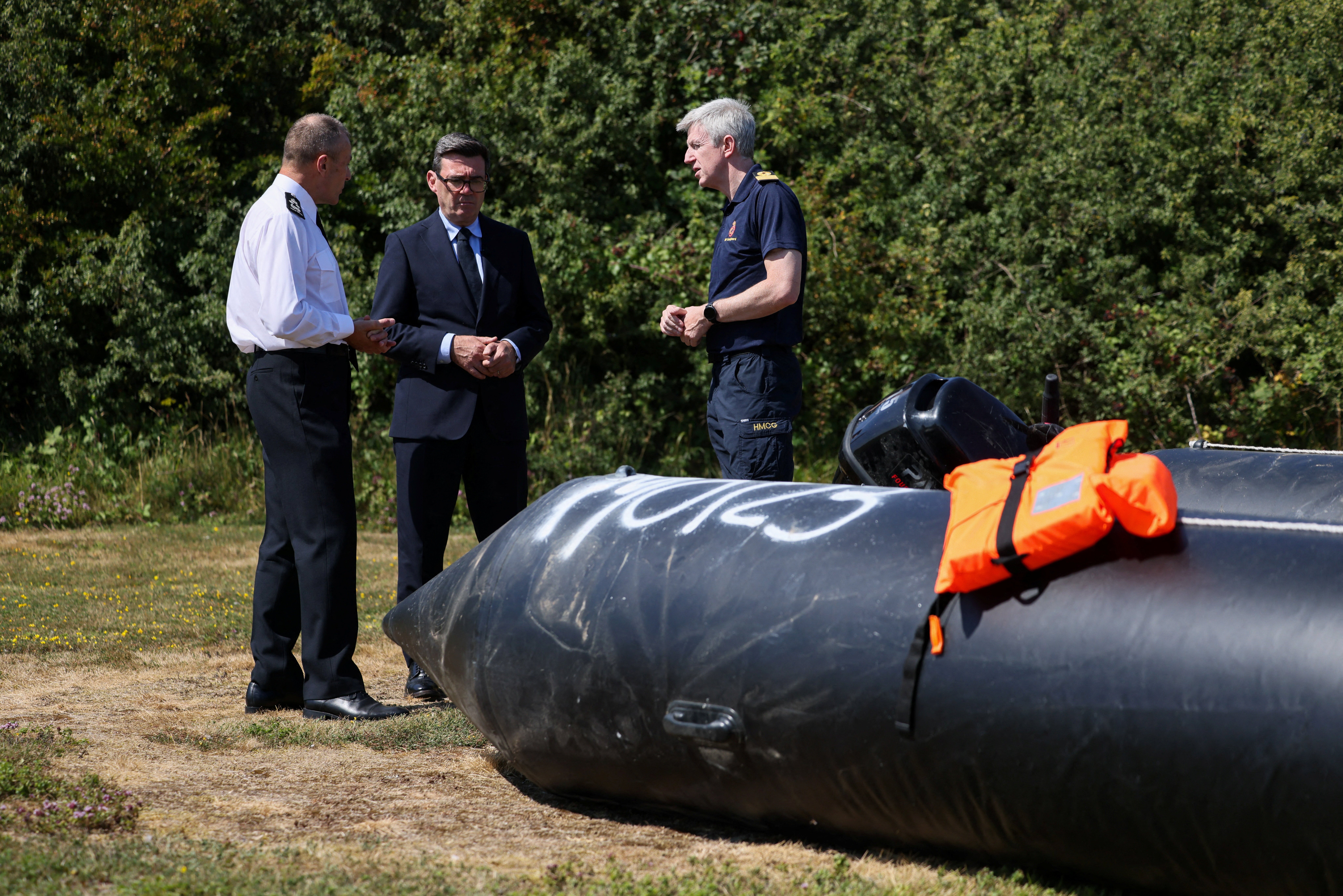 Britain's Prime Minister Andy Burnham speaks with John Craig, Interim Chief Coastguard, and Duncan Capps, Border Security Commander (DG BSC), as they stand by a recovered small inflatable boat, used by migrants crossing the English Channel (AFP/Getty)