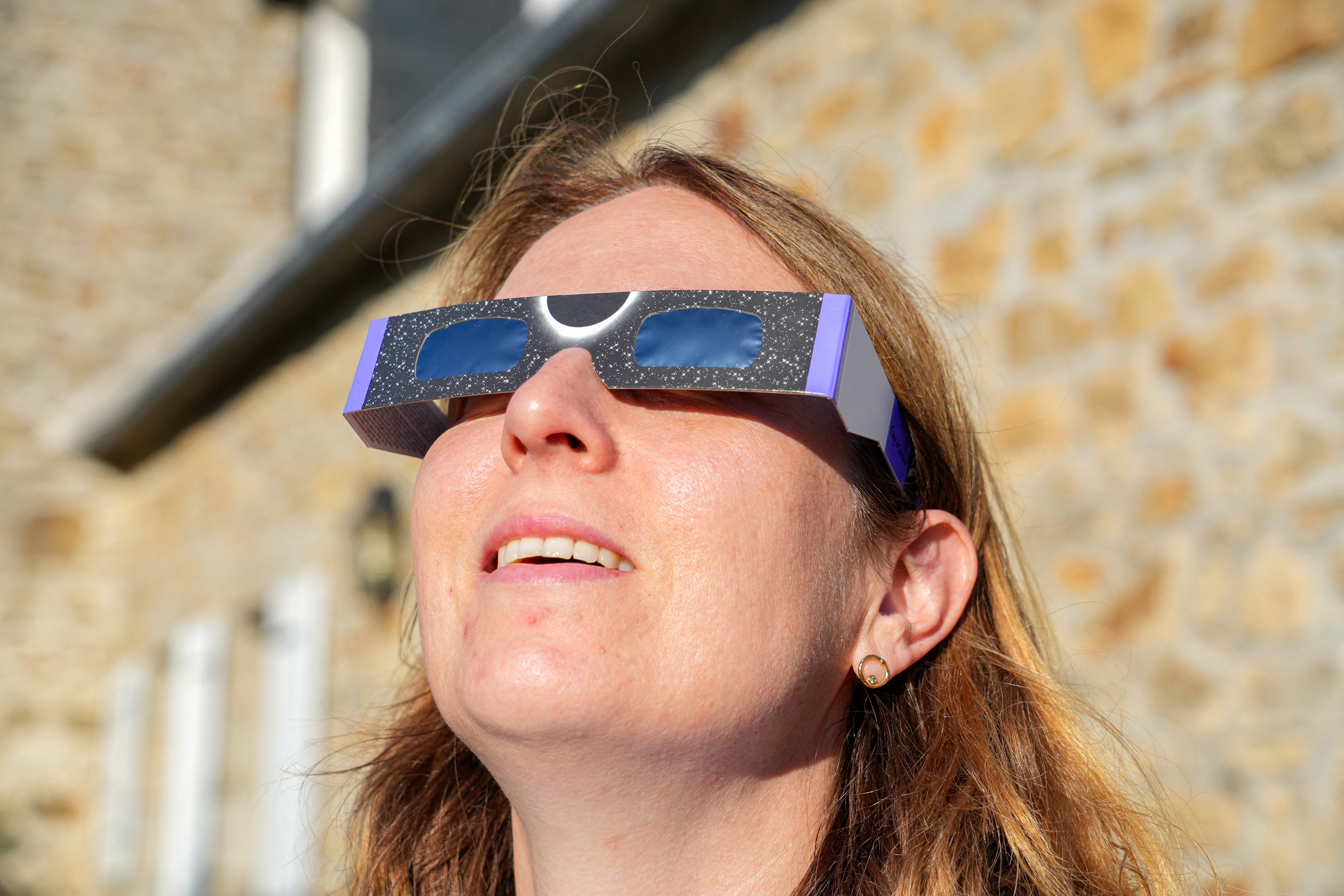 A woman is looking at the sun through a pair of special cardboard glasses designed to protect her eyes while watching the solar eclipse on August 12 in Saint-Pol-de-Leon, in the Finistere department of Brittany in western France, on August 1, 2026. (Photo by Nicolas Guyonnet / Hans Lucas / AFP via Getty Images)