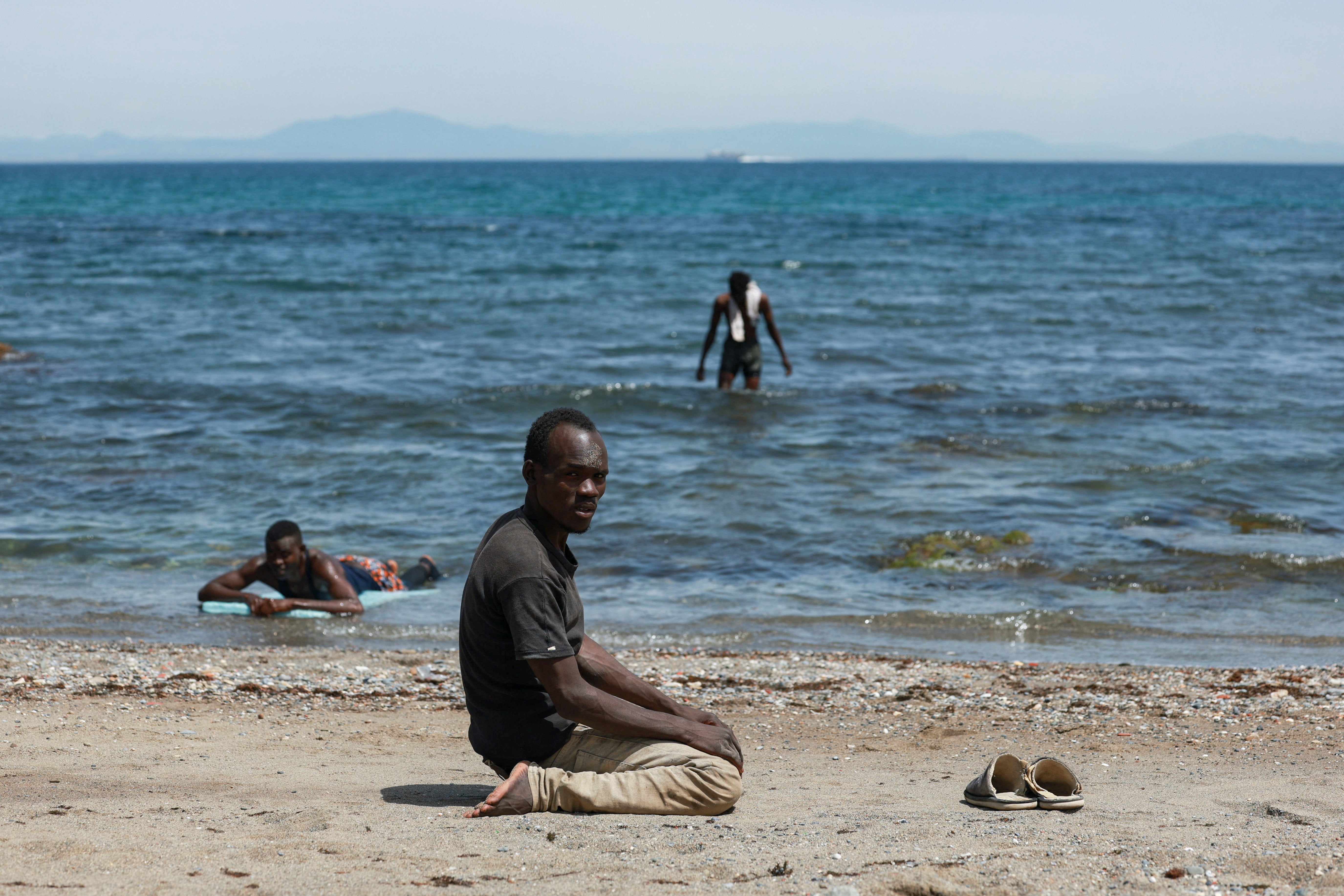 A migrant prays while waiting on the beach