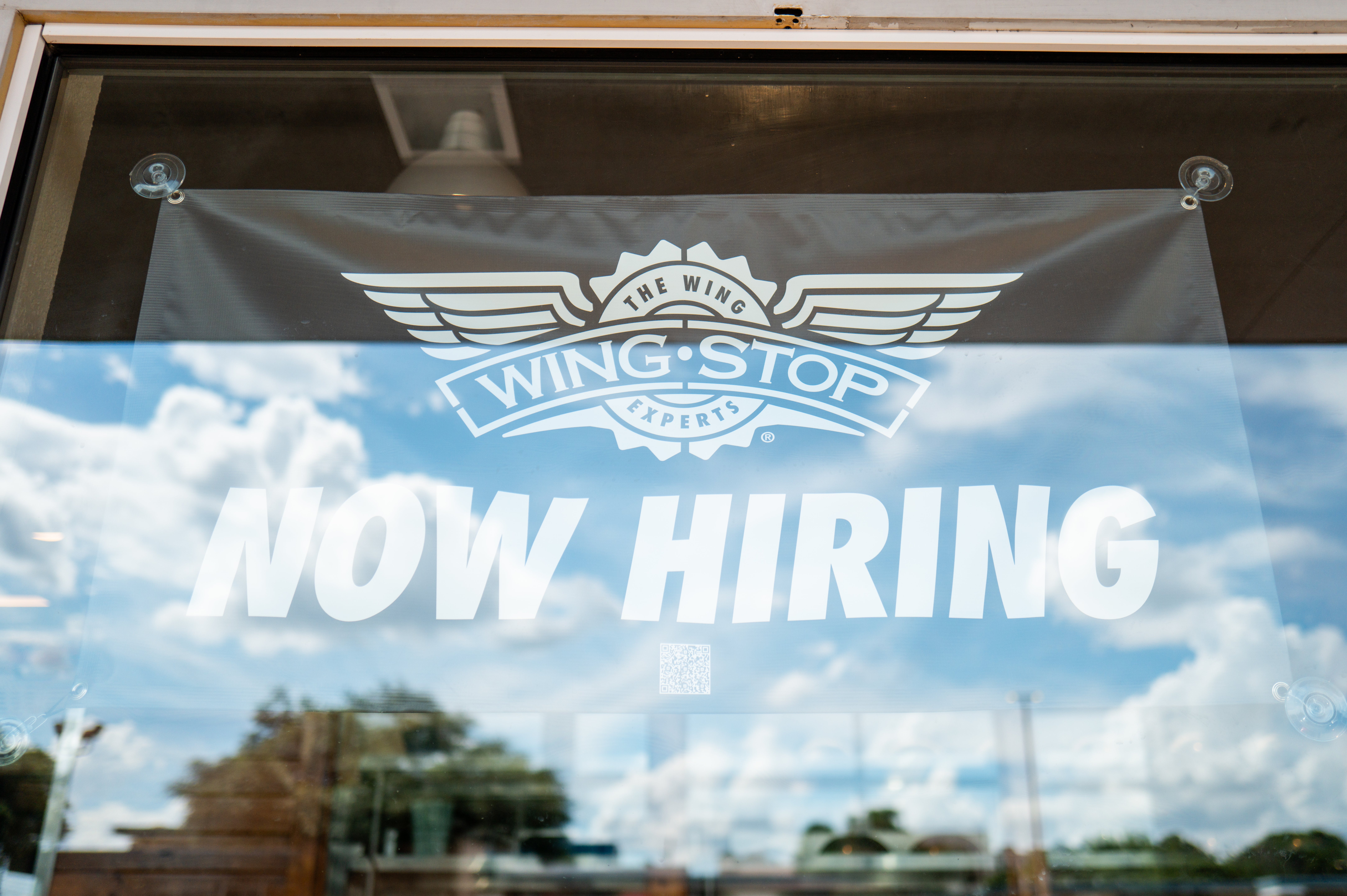 A hiring sign is displayed in a Wingstop store window on June 25, 2025 in Austin, Texas.
