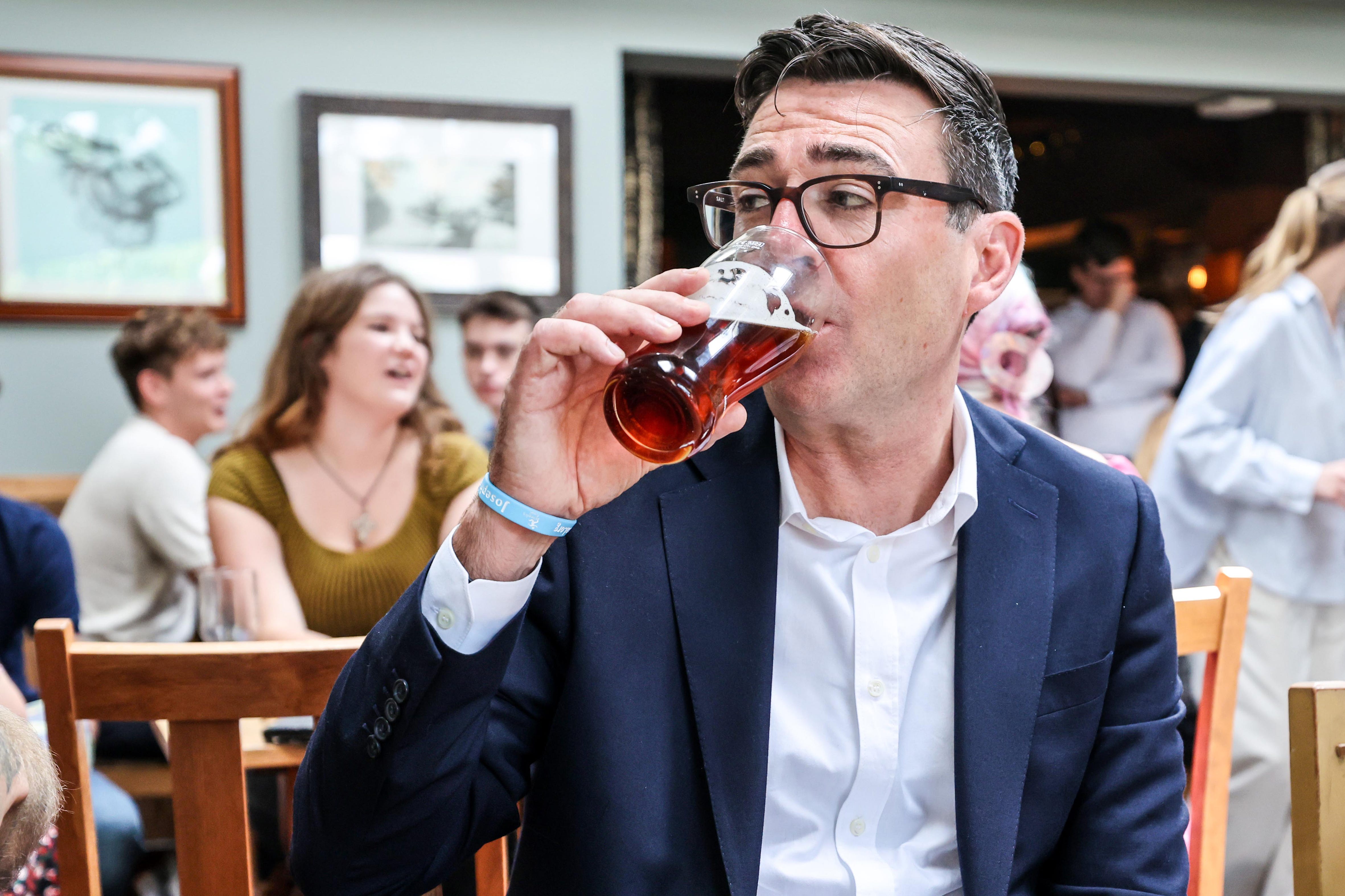 Andy Burnham drinks a beer during a visit to the Hare pub in Harlow, Essex