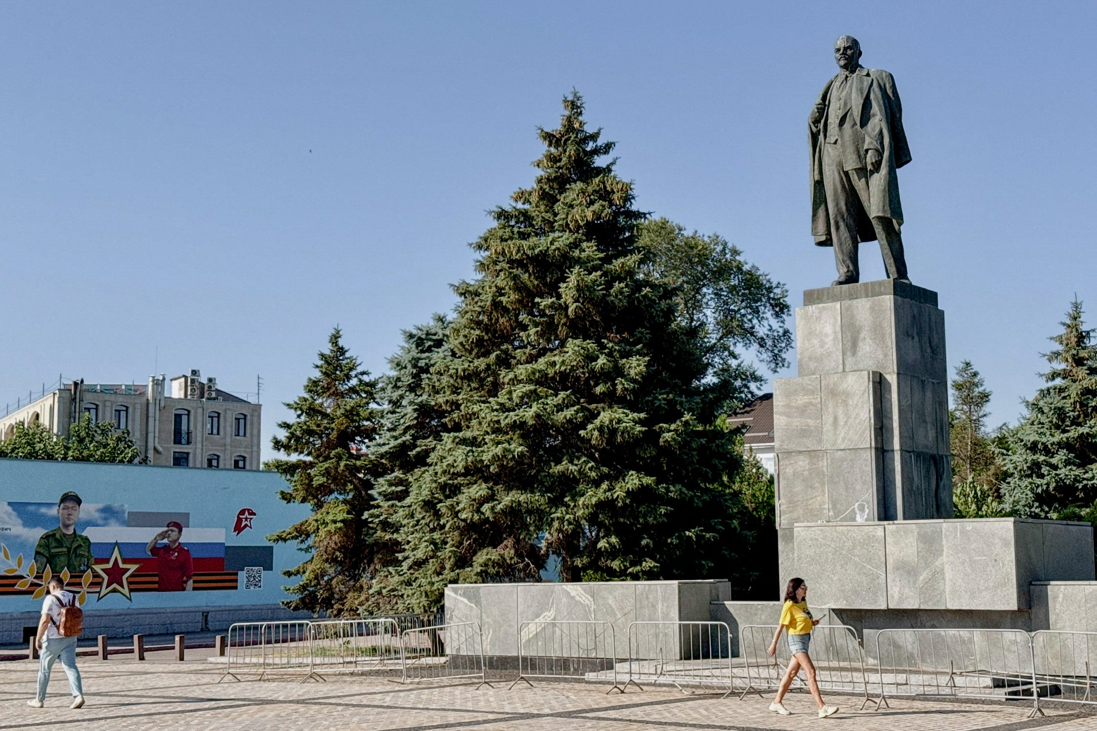 Pedestrians walk past a mural depicting the Russian Patriotic Youth movement Yunarmiya (L) and a statue of Lenin in Kerch, on the Russian-annexed peninsula of Crimea (AFP/Getty)