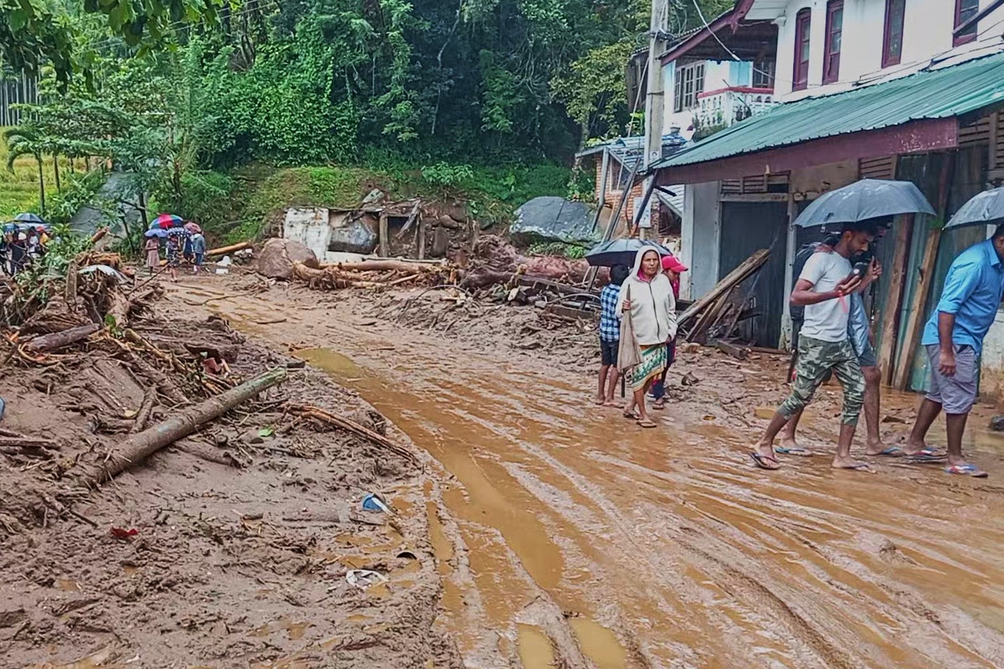 People walk across a mud covered road following heavy rain in Nawalapitiya, Sri Lanka.