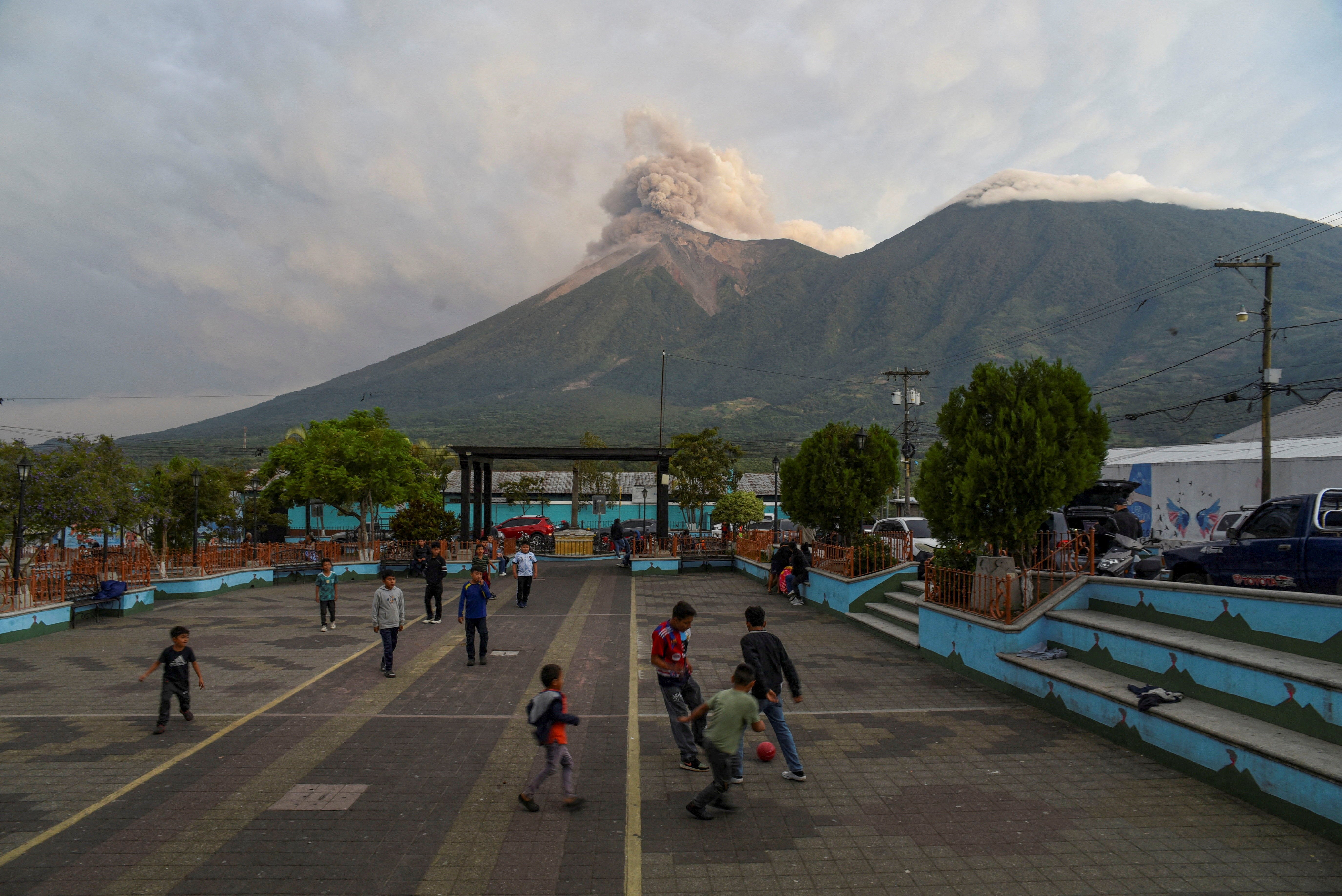 Children play as Guatemala's Fuego volcano erupts, after authorities raised the alert level to orange, as seen from San Juan Alotenango (Reuters)