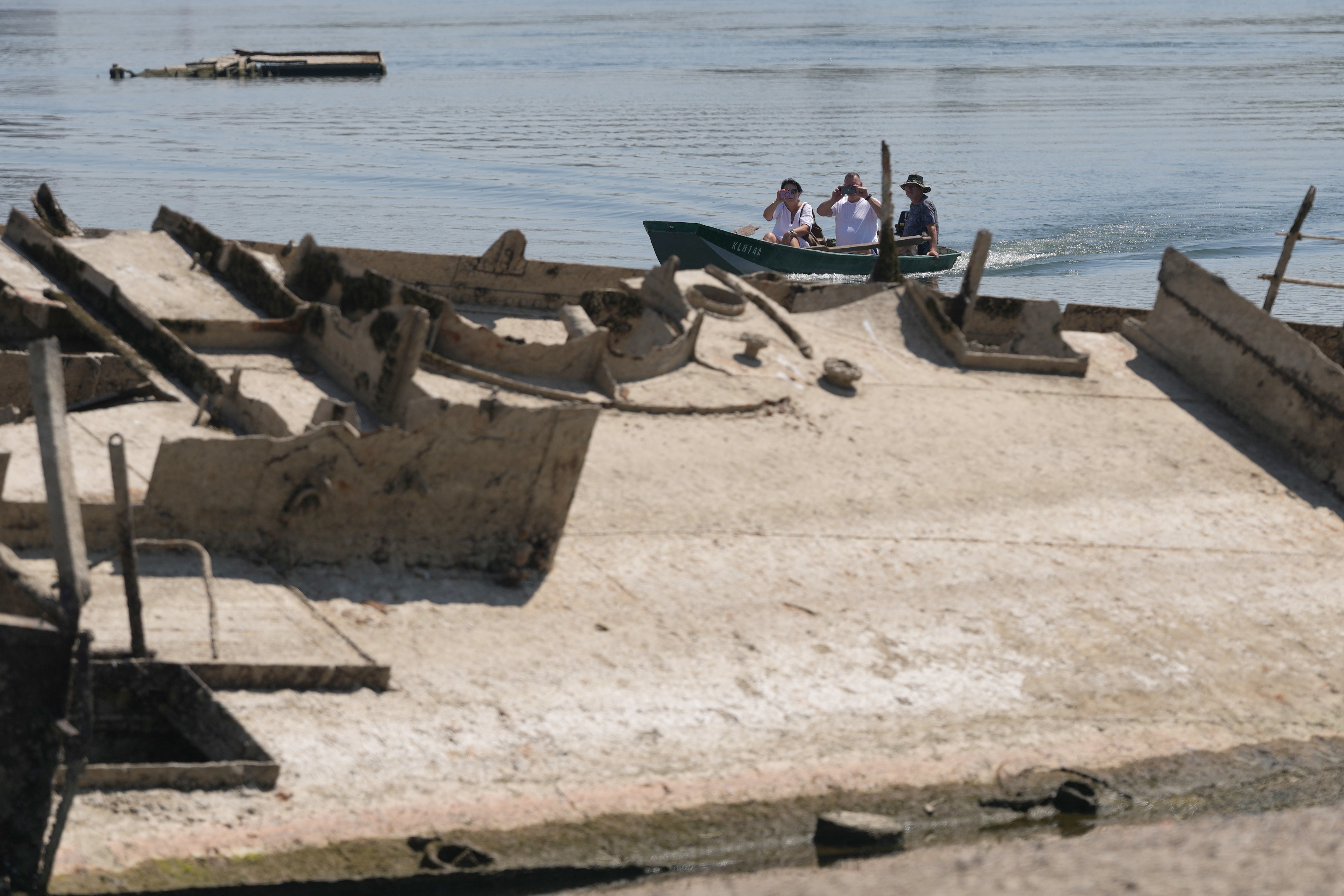 People watch the wreckage of a WWII German warship, emerged due to the drought, in front of Djerdap II, a large dam on the Danube River, between Romania and Serbia, near Prahovo, Serbia, Tuesday, Aug. 4, 2026. (AP Photo/Darko Vojinovic) (Copyright 2026 The Associated Press. All rights reserved)