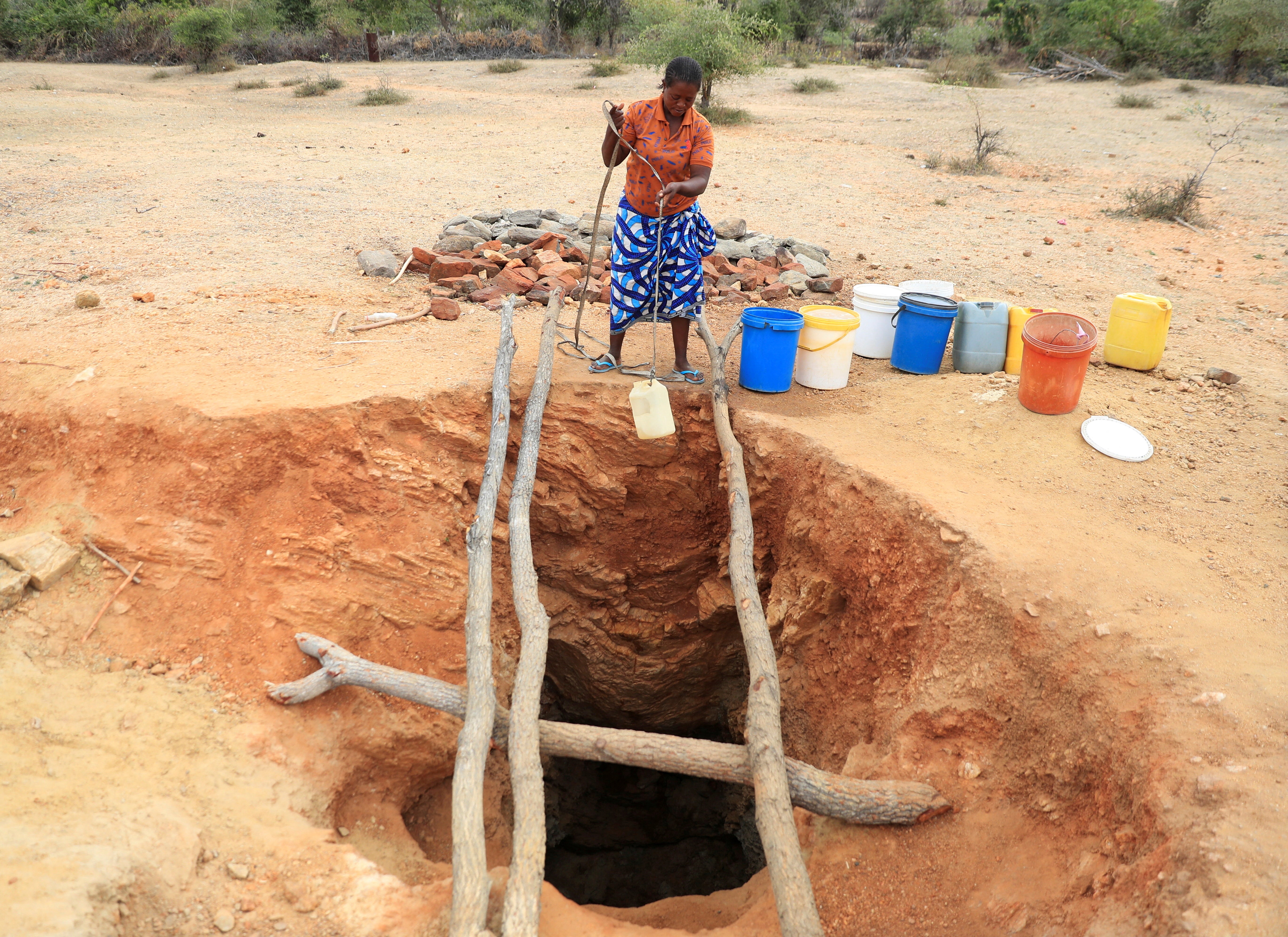A woman fetches drinking water from an unprotected well, as Zimbabwe is experiencing an El Nino-induced drought