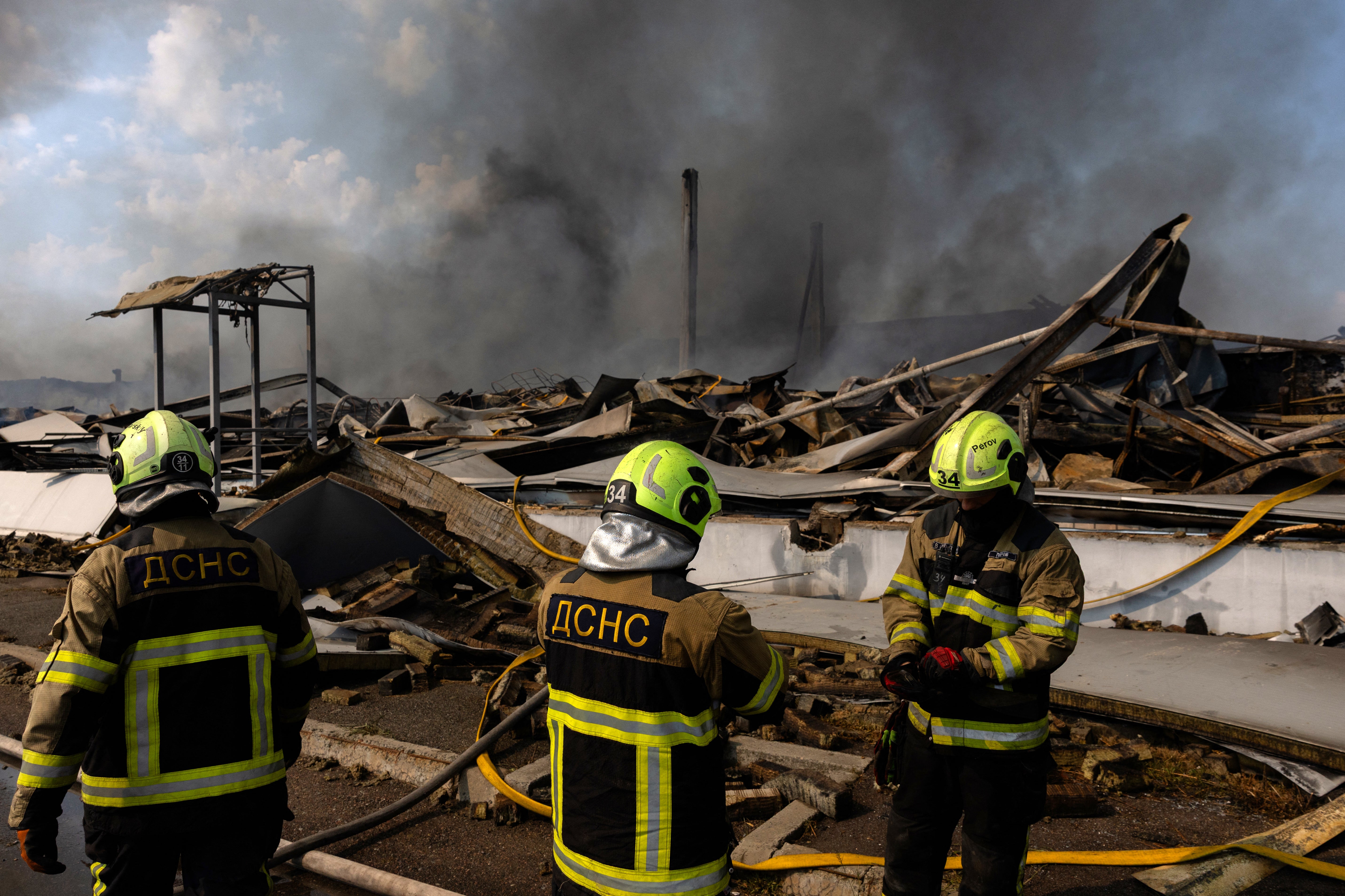 Ukrainian firefighters work to put out a fire following massive Russian ballistic missile and drone strikes in Kyiv