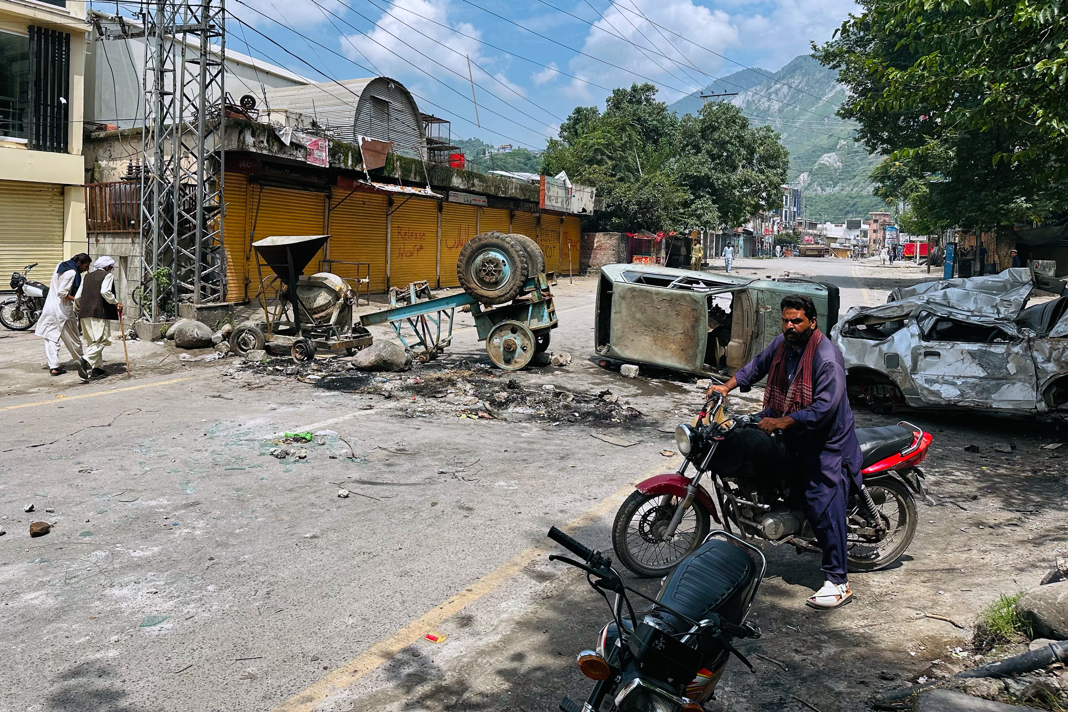 A motorcyclist navigates a road barricaded by supporters of the outlawed Jammu Kashmir Joint Awami Action Committee in Muzaffarabad