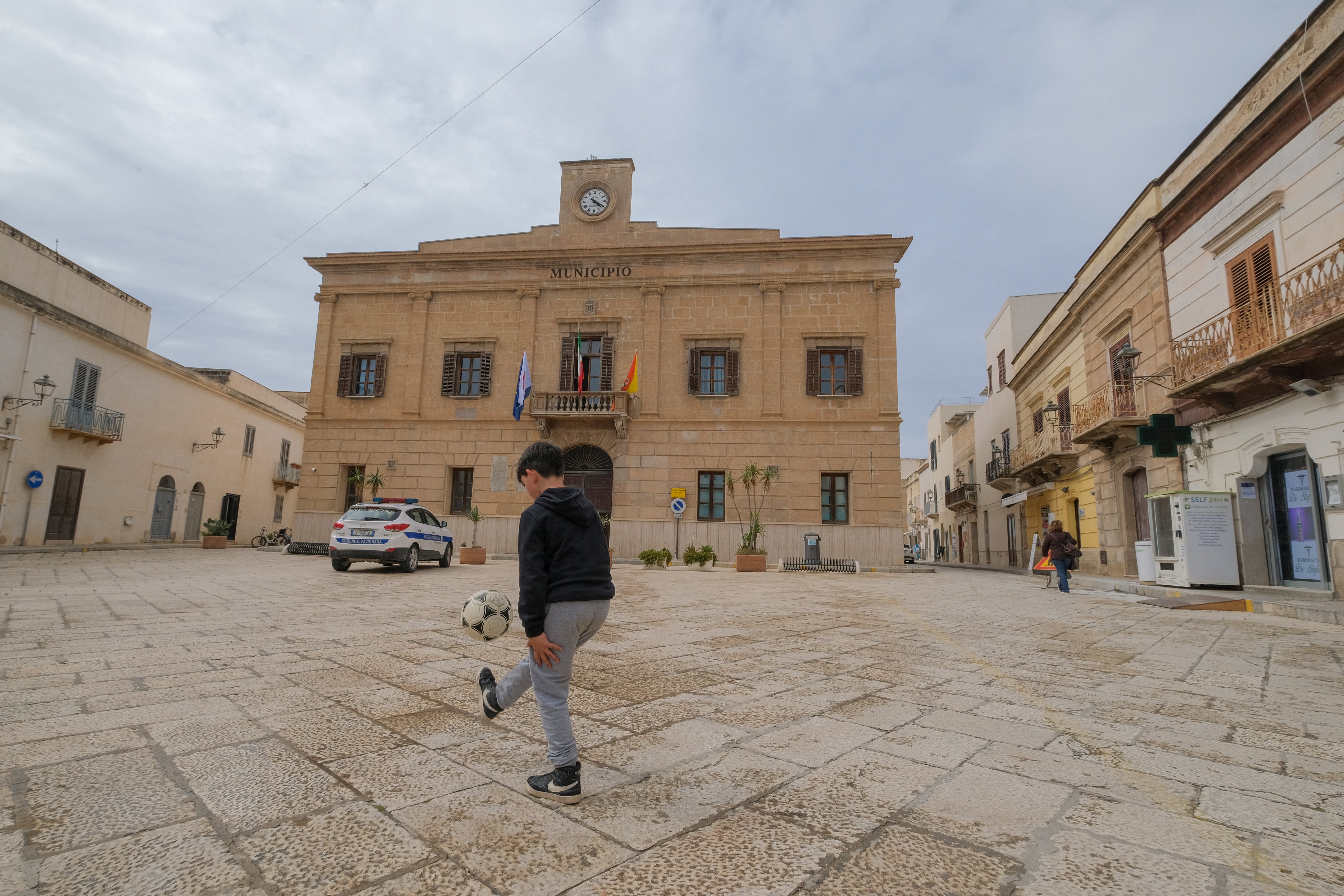 A boy plays football outside Favignana's municipal building
