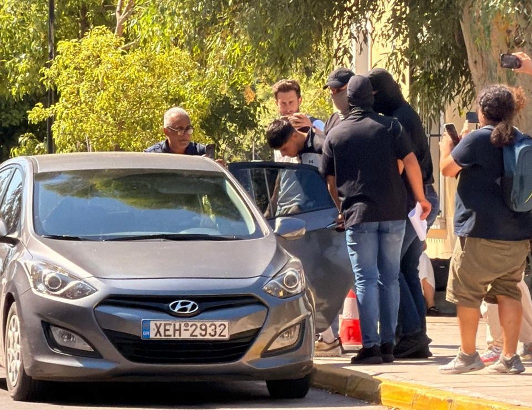 Sharif Ahmadzai is led out of the Athens Courthouse complex in Kypseli (PA)