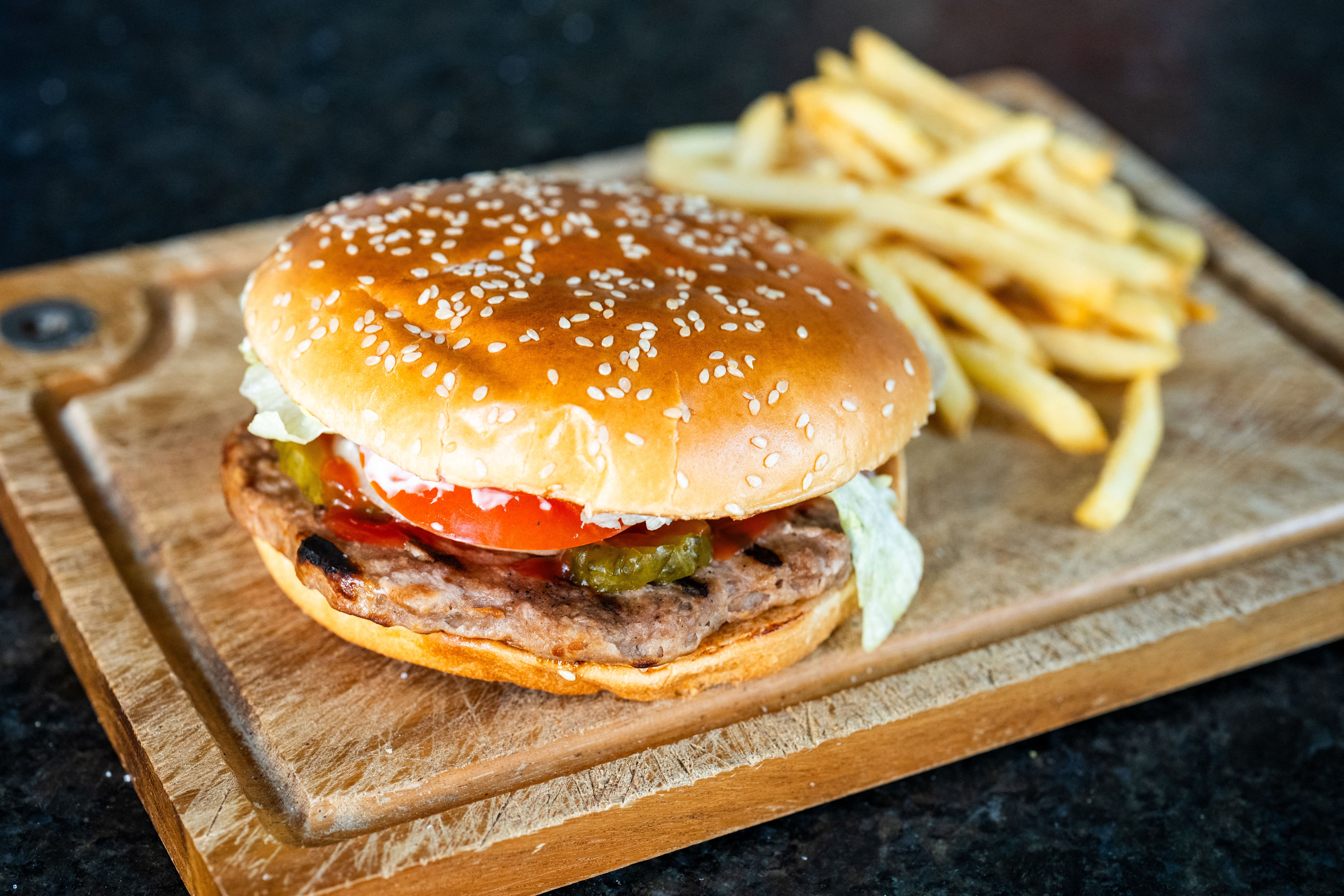 A photo shows a vegetarian hamburger 'veggie burger' with a side of fries on a wooden cutting board