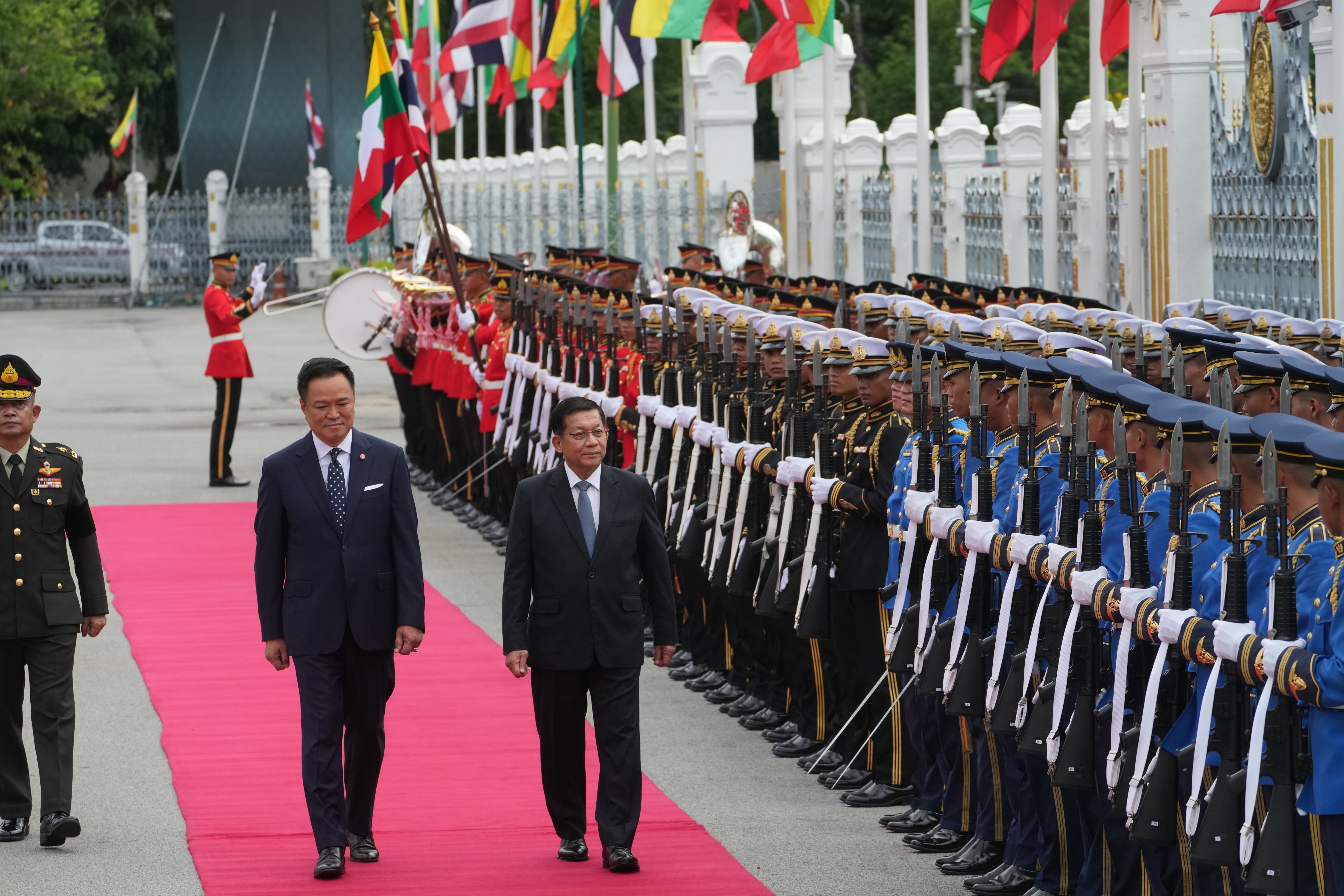Anutin Charnvirakul, centre left, and Min Aung Hlaing review an honor guard during a welcome ceremony in Bangkok (AP)