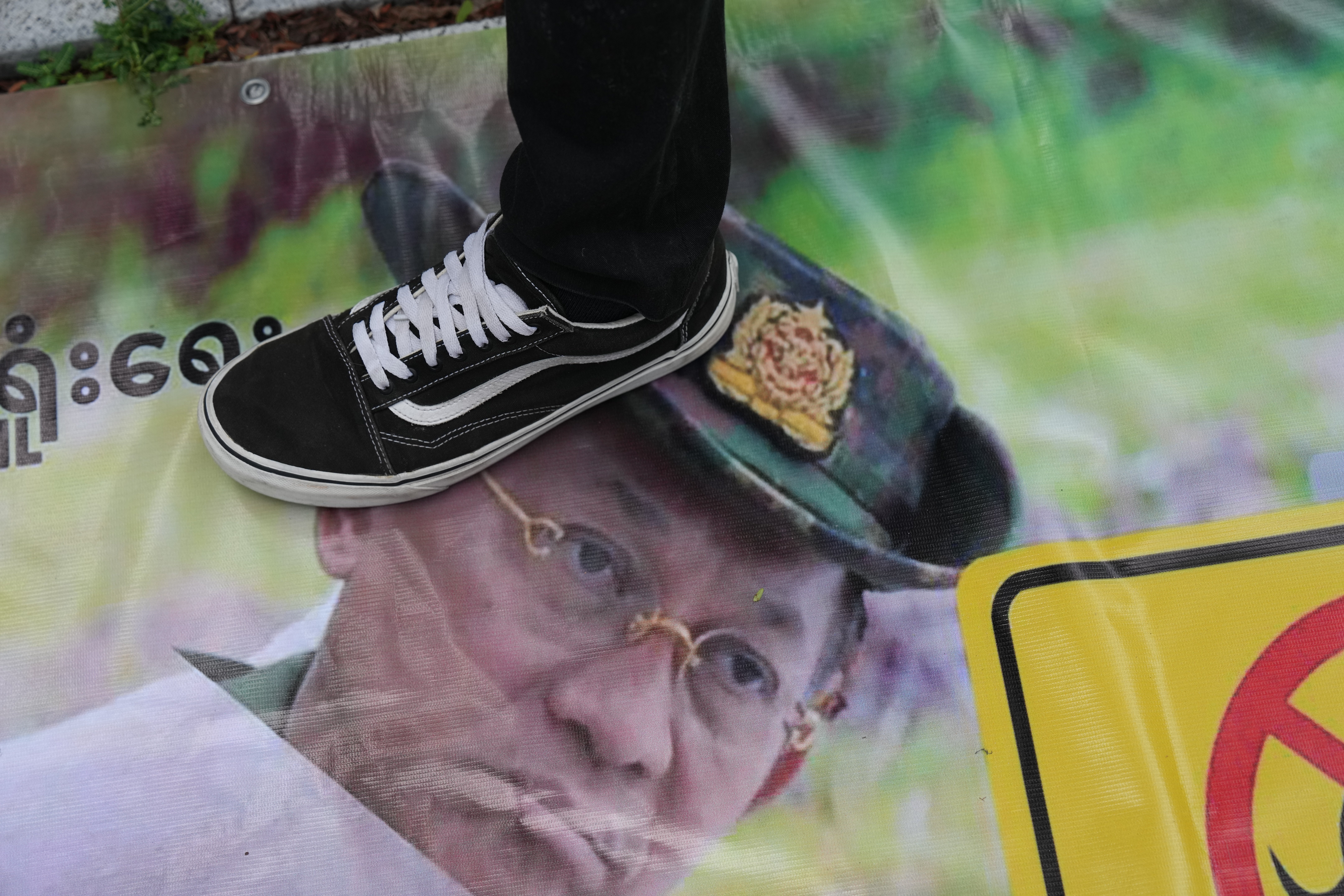 A Myanmarese national living in Thailand steps on a poster of Min Aung Hlaing during a protest in Bangkok (AP)