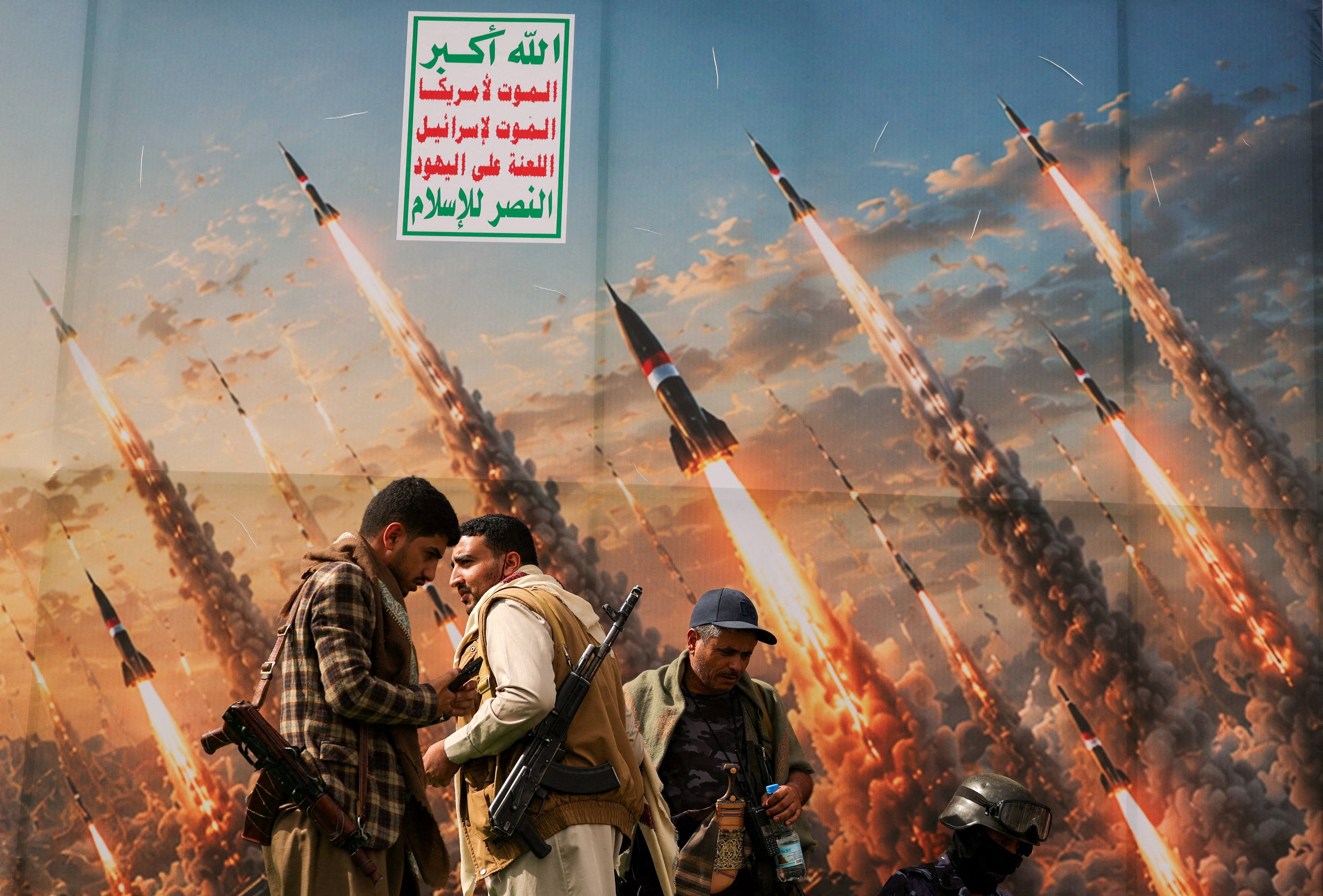 Houthi activists stand on a platform against a banner depicting Houthi missiles, at an anti-Saudi rally amid an escalation with the kingdom
