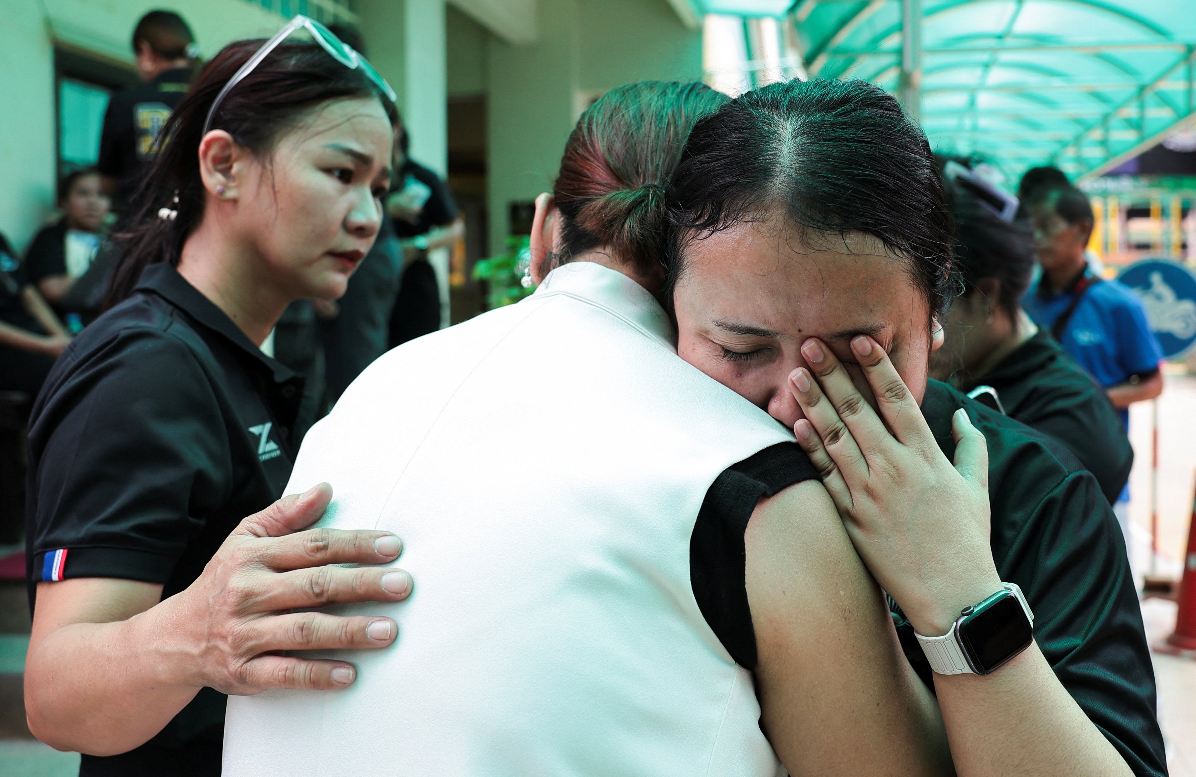 A teacher reacts while embracing a person at Debsirin Nonthaburi School