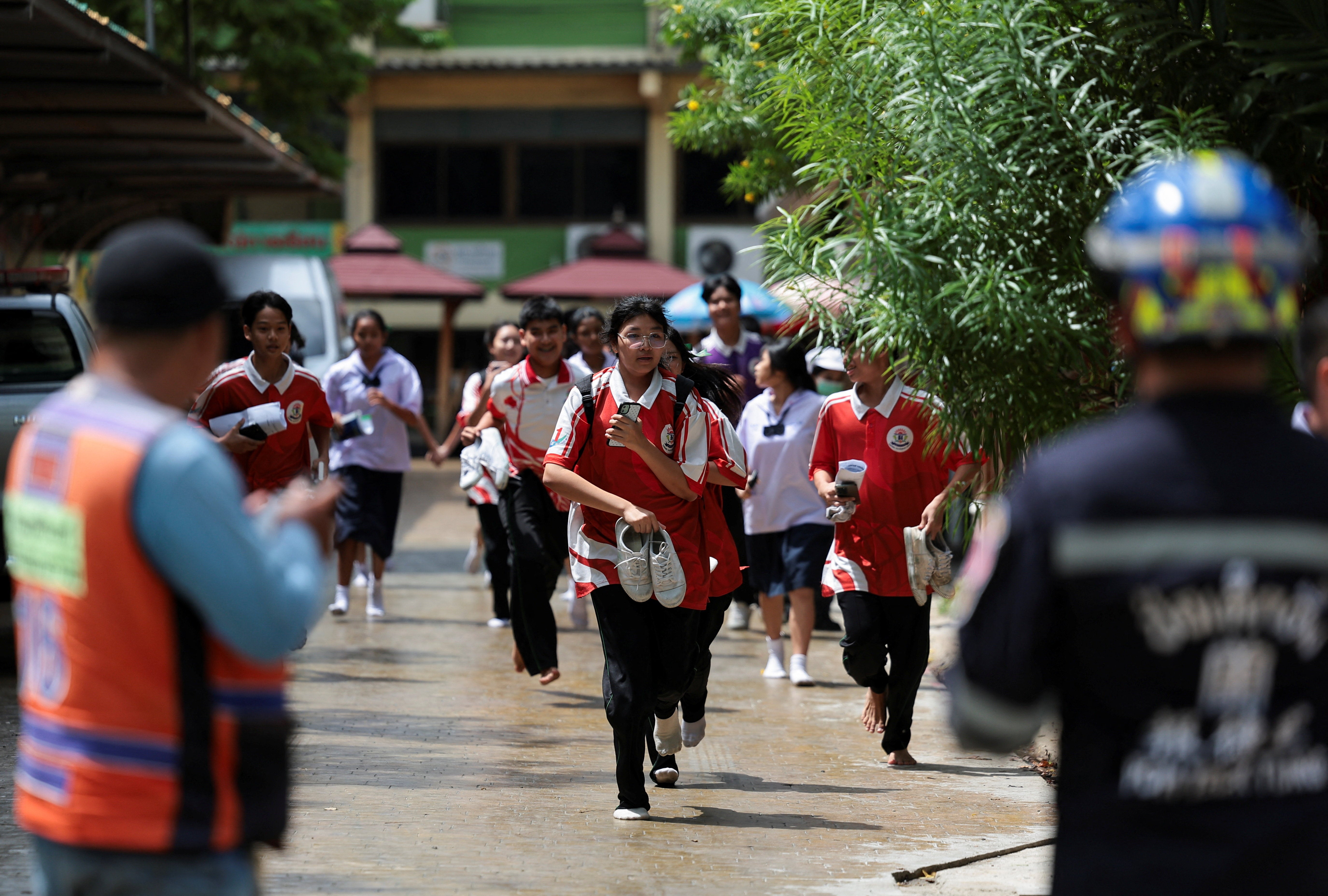 Students run as they evacuate from Debsirin Nonthaburi School, the site of a shooting incident, in Bang Kruai district