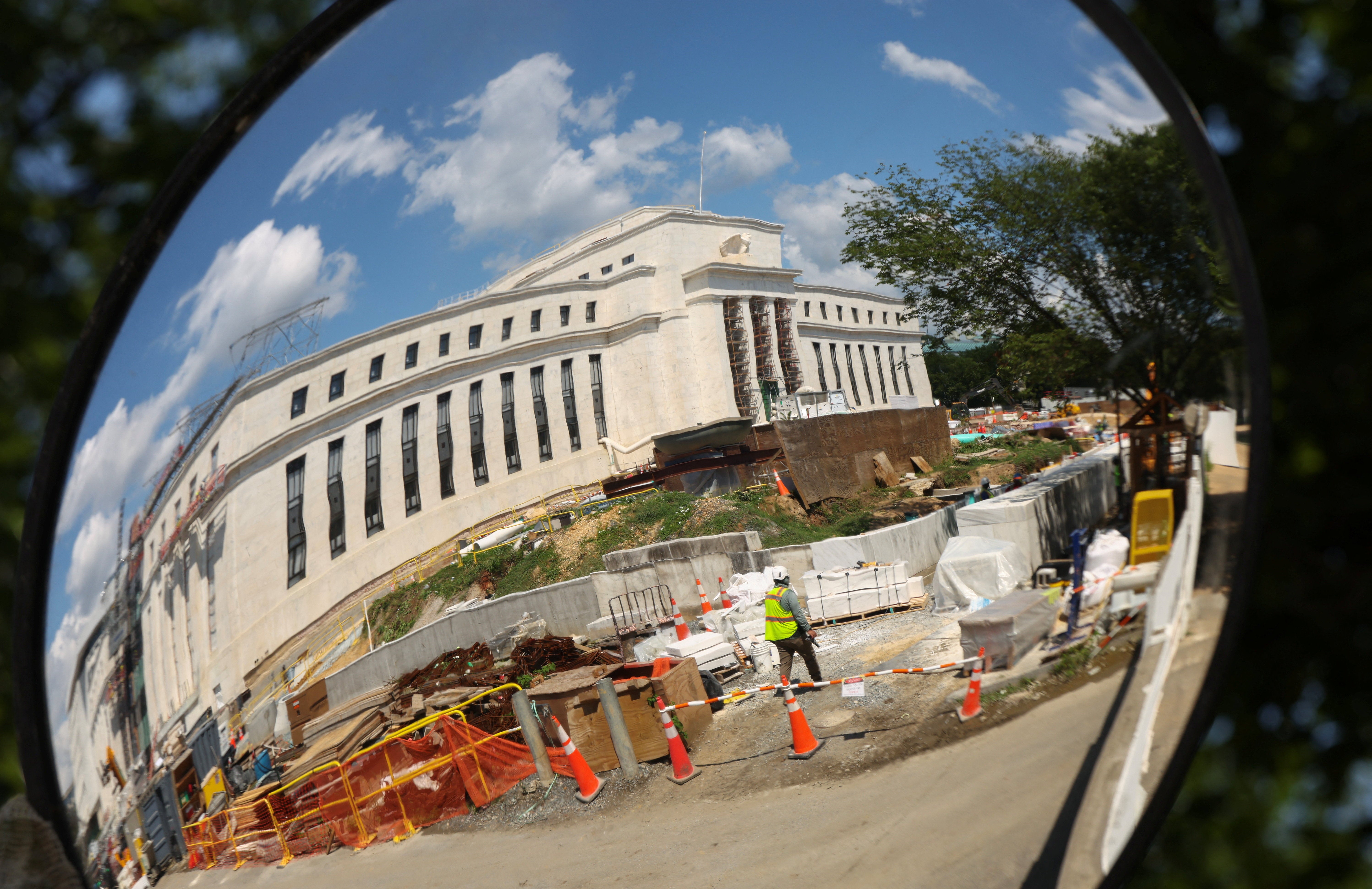 The Federal Reserve headquarters, where construction continues, is reflected in a mirror in Washington (Reuters)
