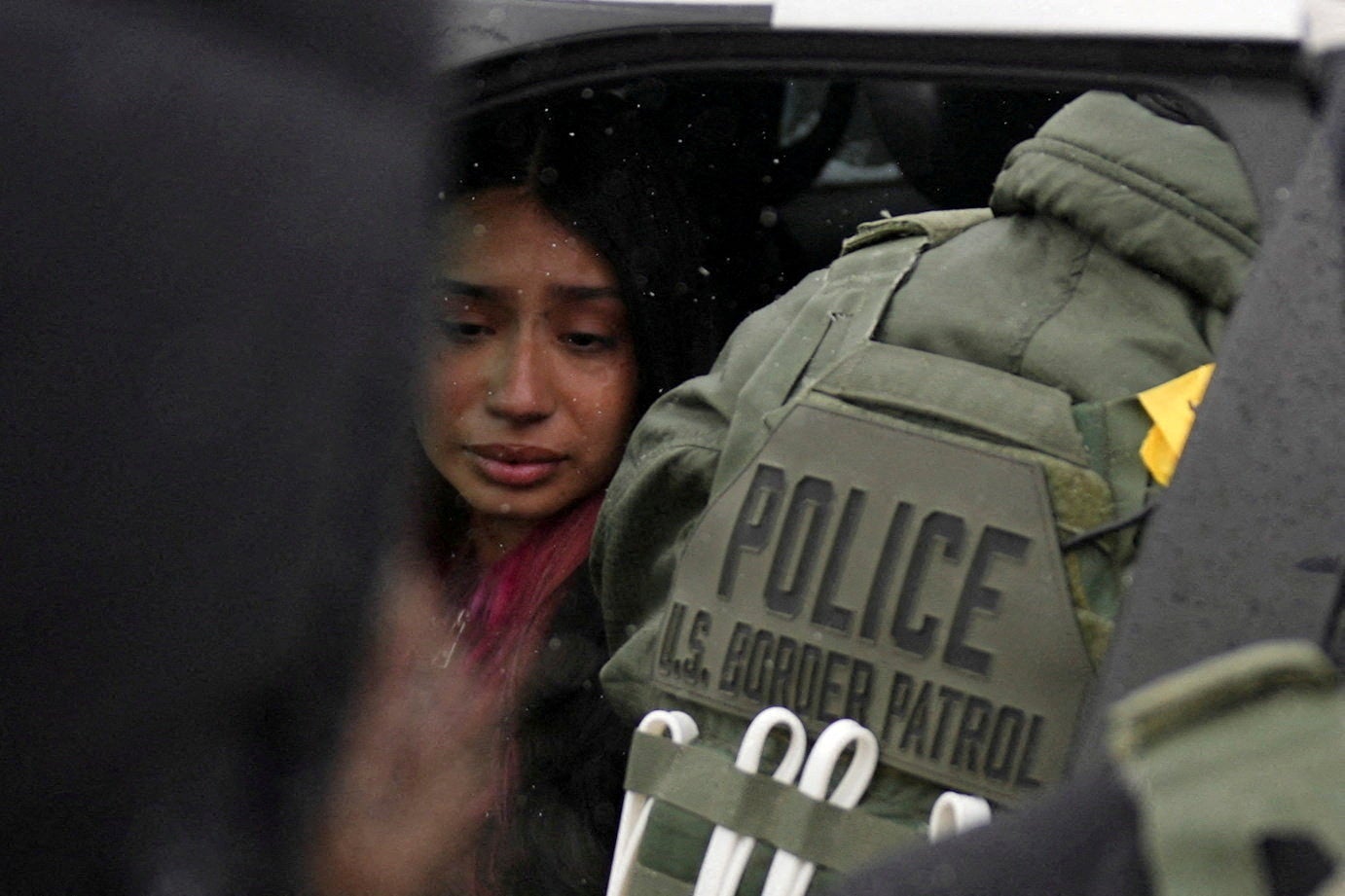 A detained woman sits inside a vehicle surrounded by federal agents, as immigration enforcement continues after a U.S. Immigration and Customs Enforcement (ICE) agent fatally shot Renee Nicole Good on January 7 (Reuters)