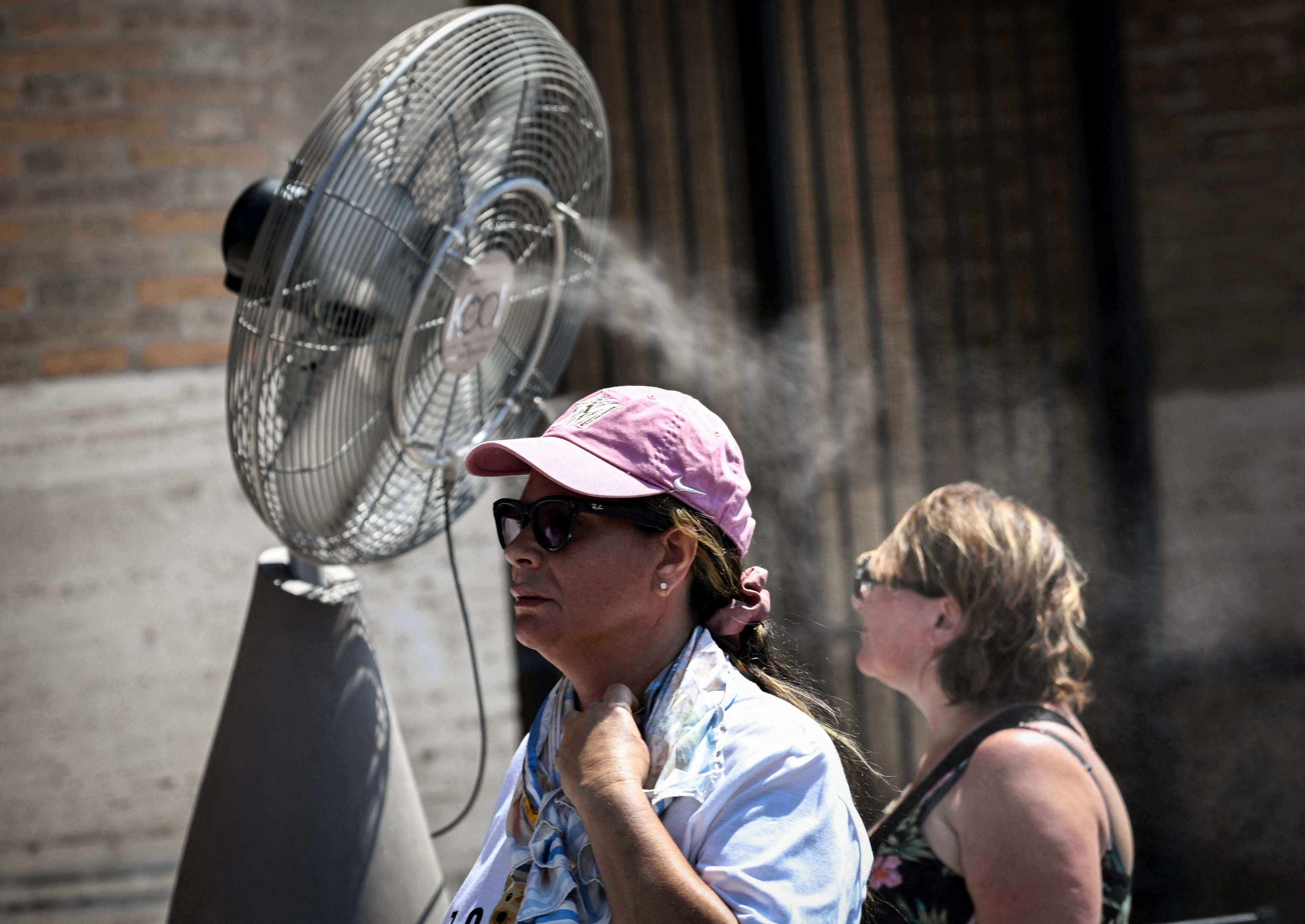People walk past a misting fan during a heatwave in Rome at the Colosseum, on 6 August 2026