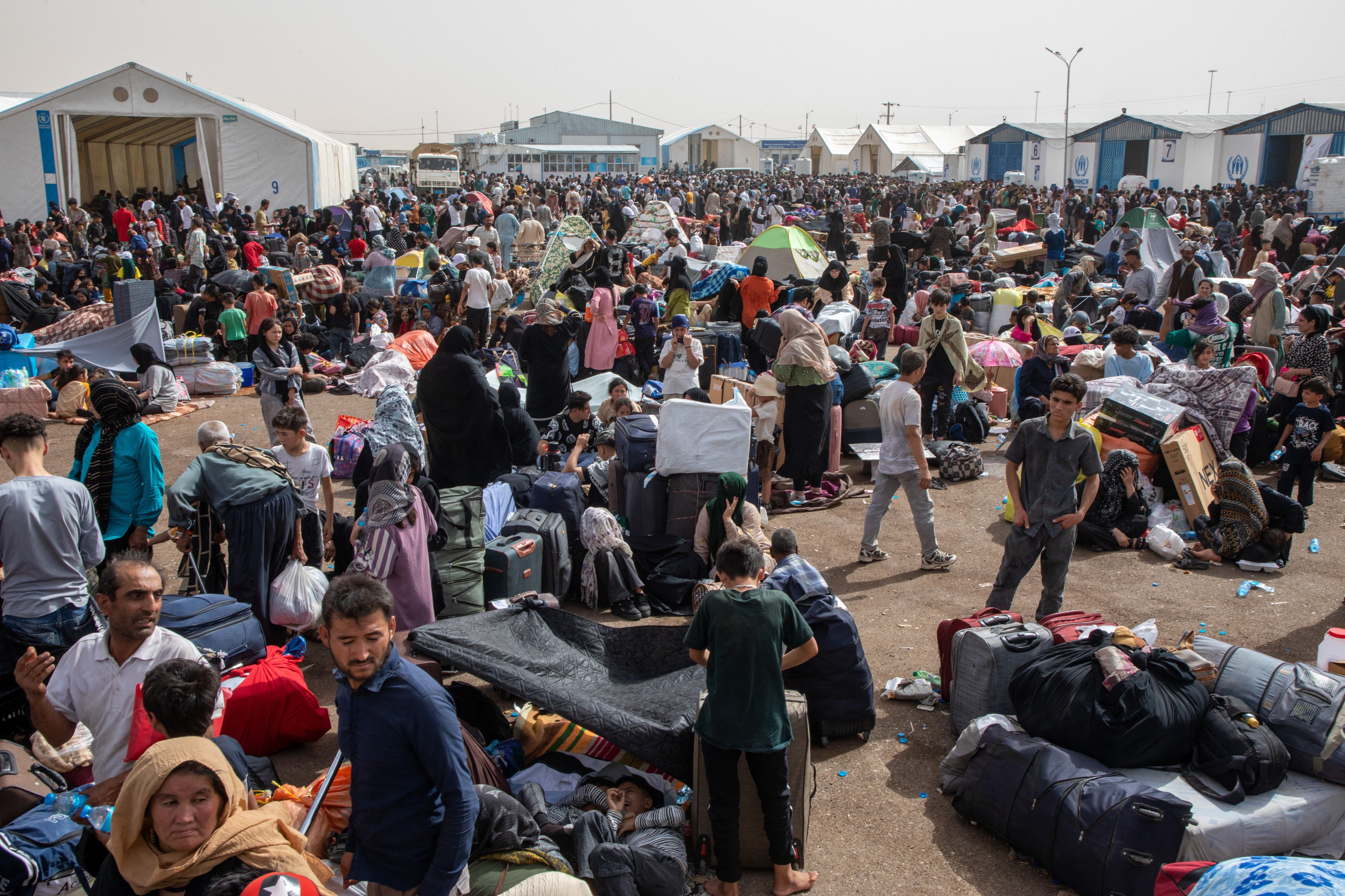 Afghan deportees sit near the border at Islam Qala crossing on 4 July 2025. Mass expulsions from Iran surged after the start of the US-Israel offensives (Middle East Images/AFP via Getty)