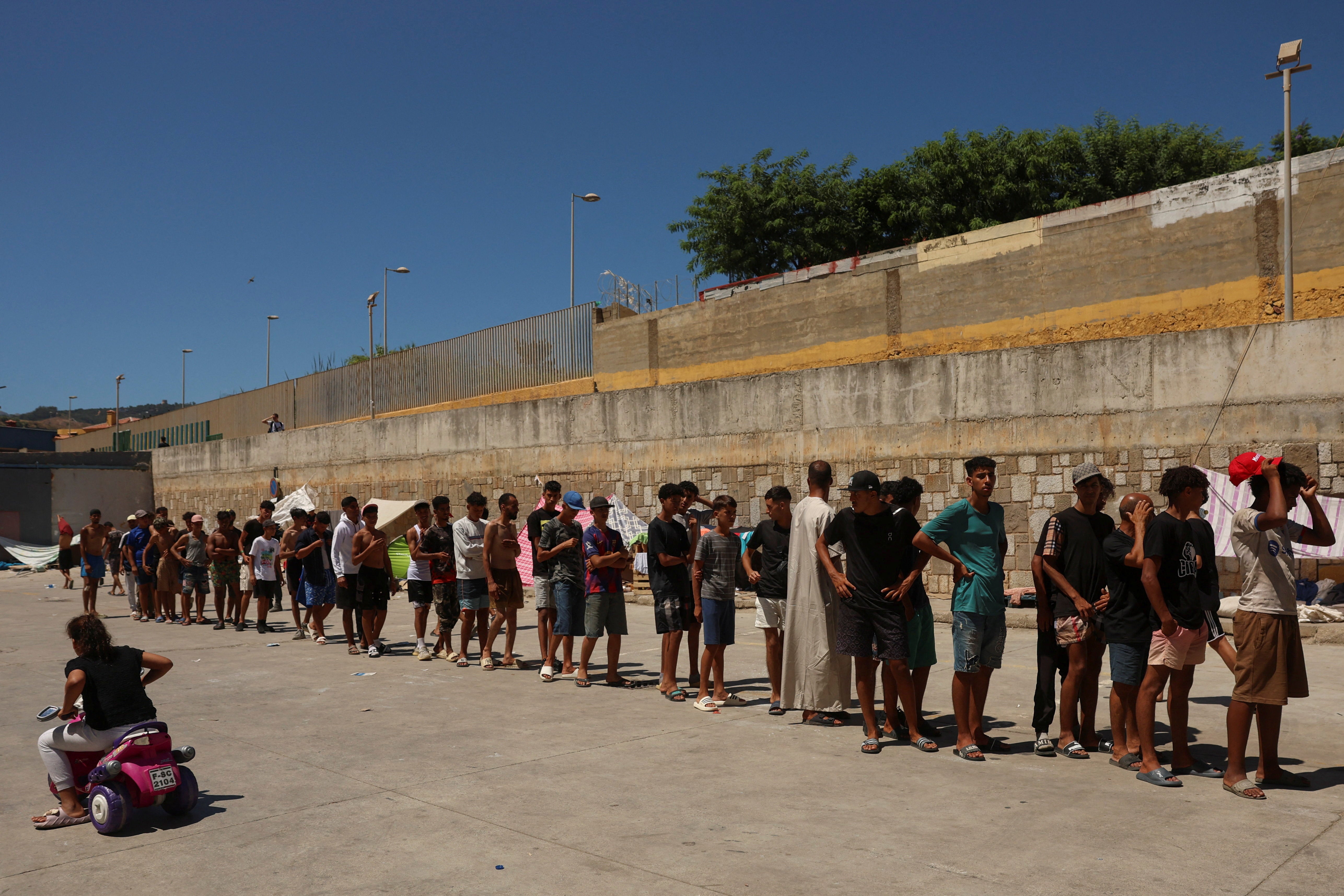 Migrants queue to receive food staples in an industrial area where they are sleeping amid recent mass crossings by migrants on foot and by sea from Morocco into the Spanish territory, in Ceuta, Spain. (Reuters)