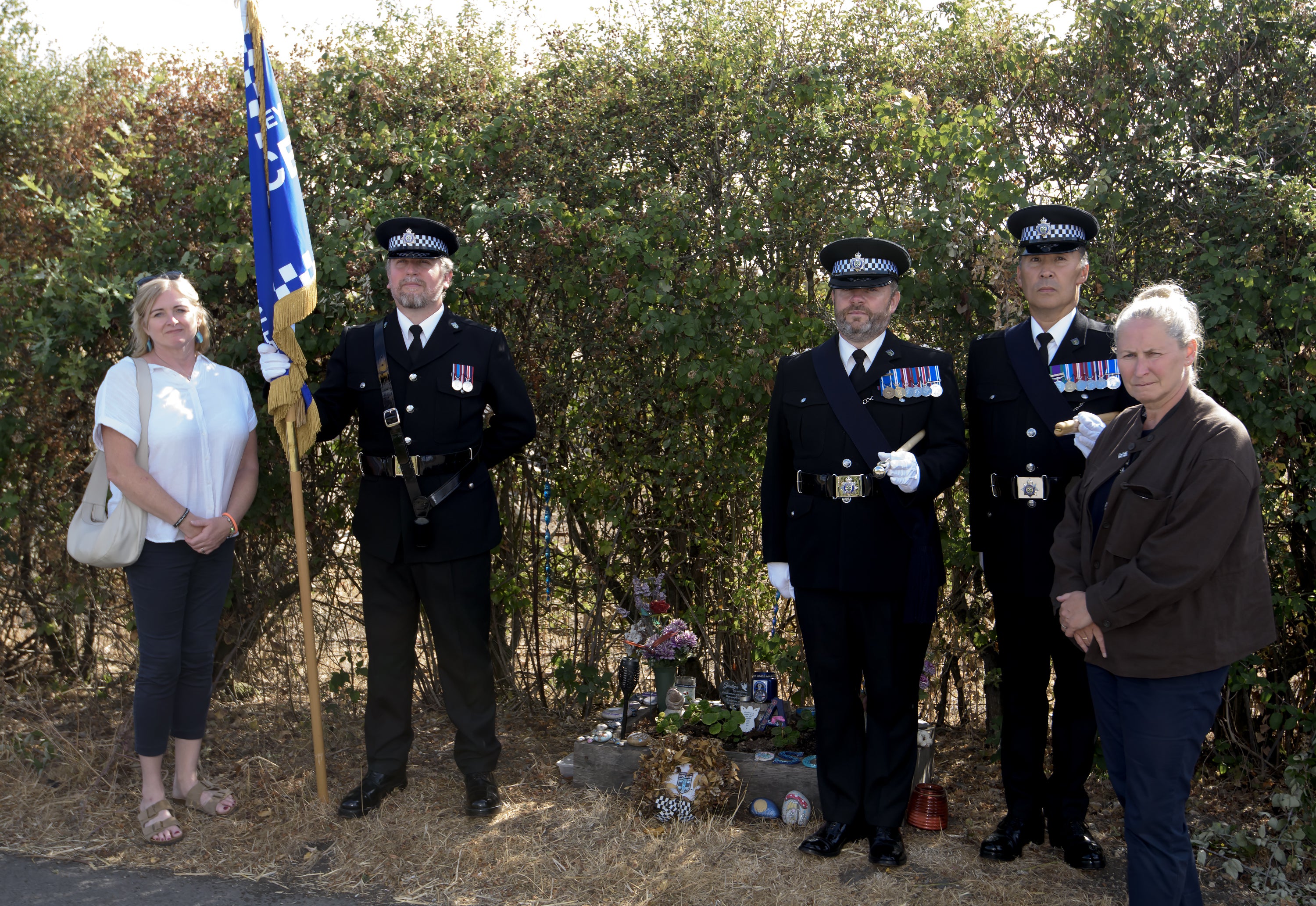 Police officers and Debbie Adlam, the mother of Pc Andrew Harper, paying their respects at the site near Sulhamstead, Berkshire, where the officer was killed