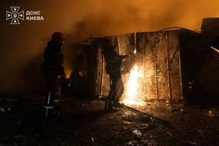 Firefighters work to douse fire at a car garage damaged during overnight Russian missile strikes