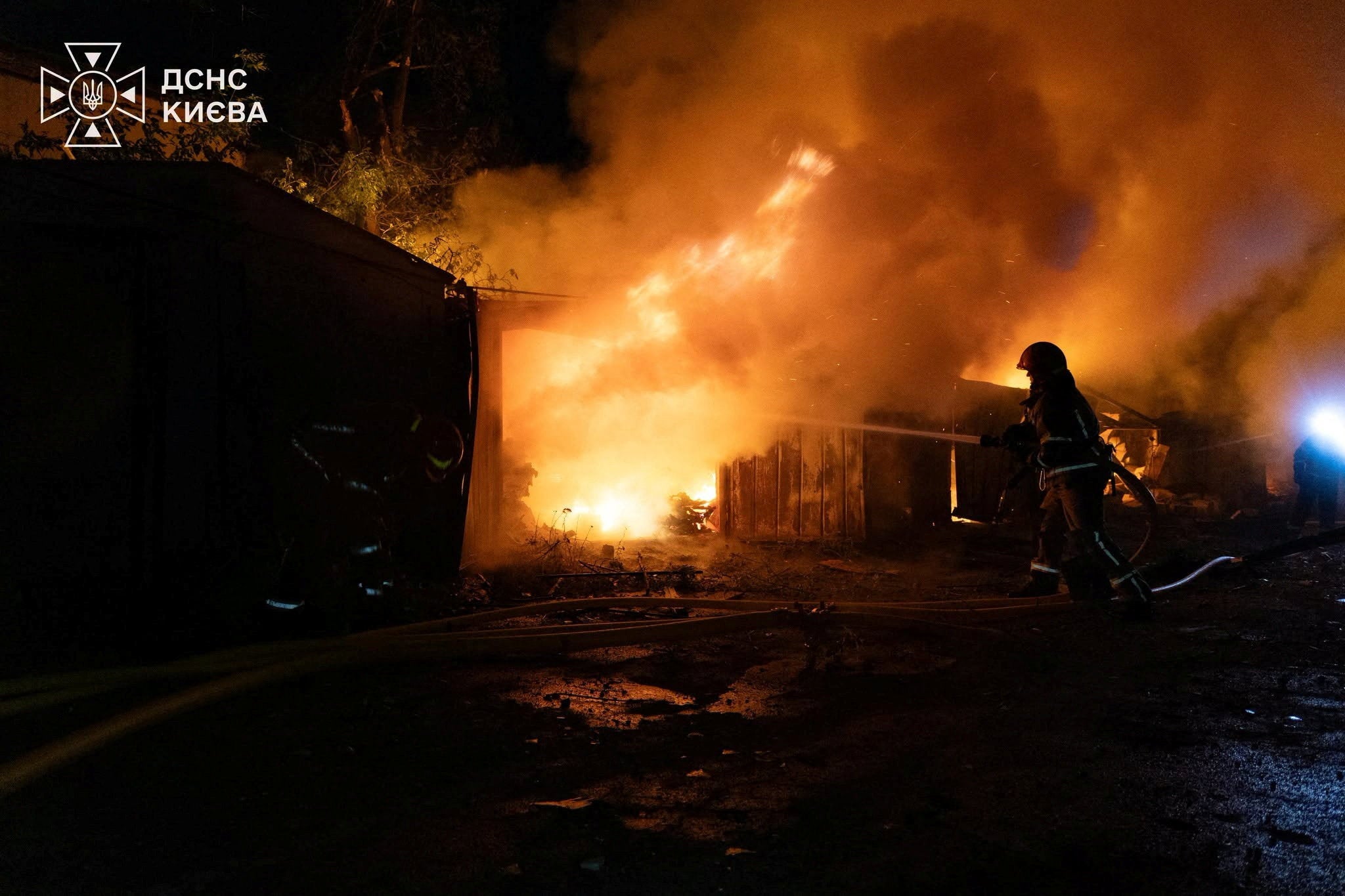 Firefighters work at a compound of car garages damaged during overnight Russian missile strikes in Kyiv