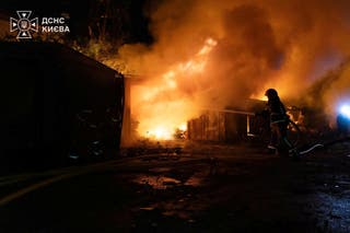 Firefighters work at a compound of car garages damaged during overnight Russian missile strikes in Kyiv