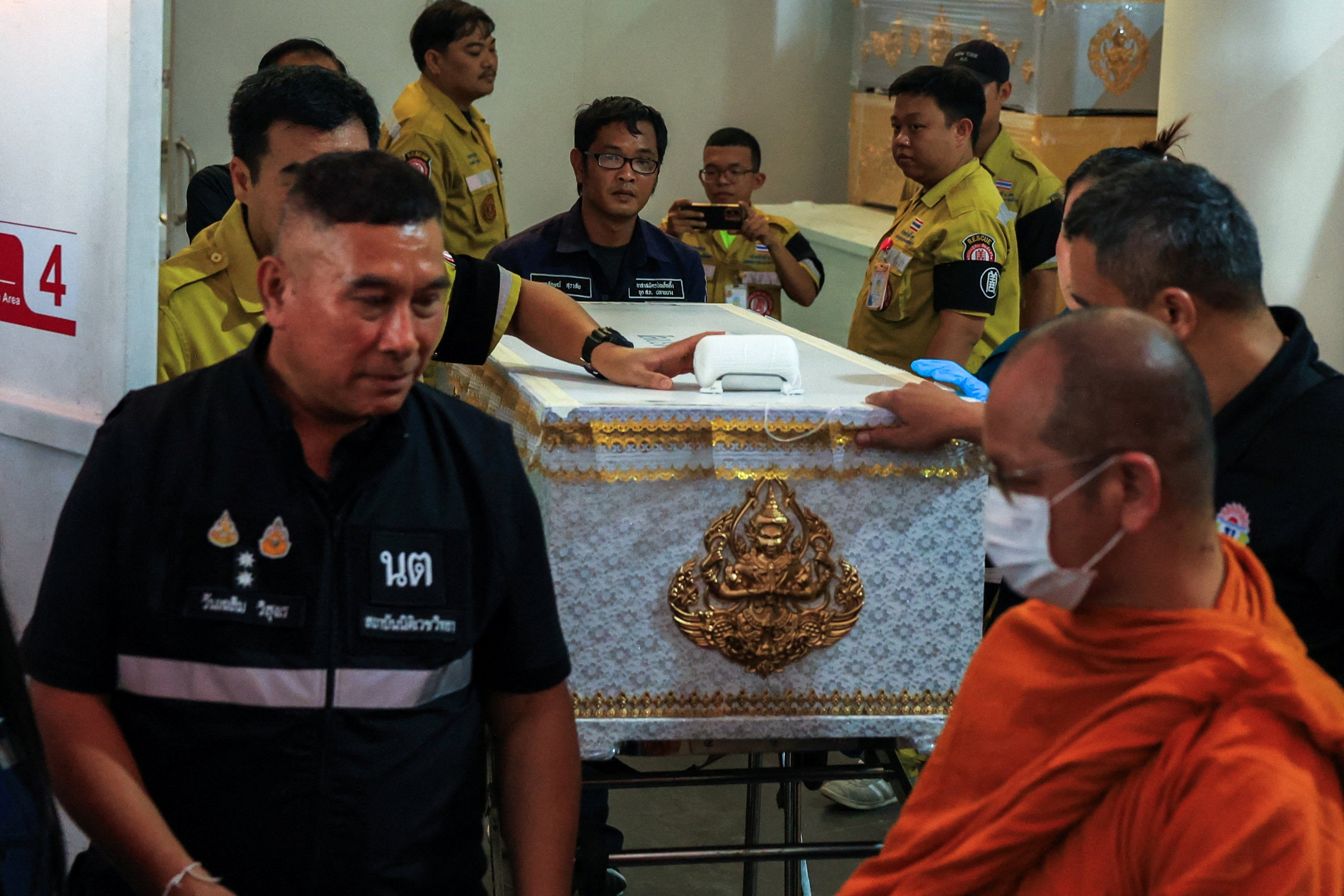 A Buddhist monk leads as workers move a coffin with the body of a victim killed in a deadly shooting at Debsirin Nonthaburi School (Reuters)