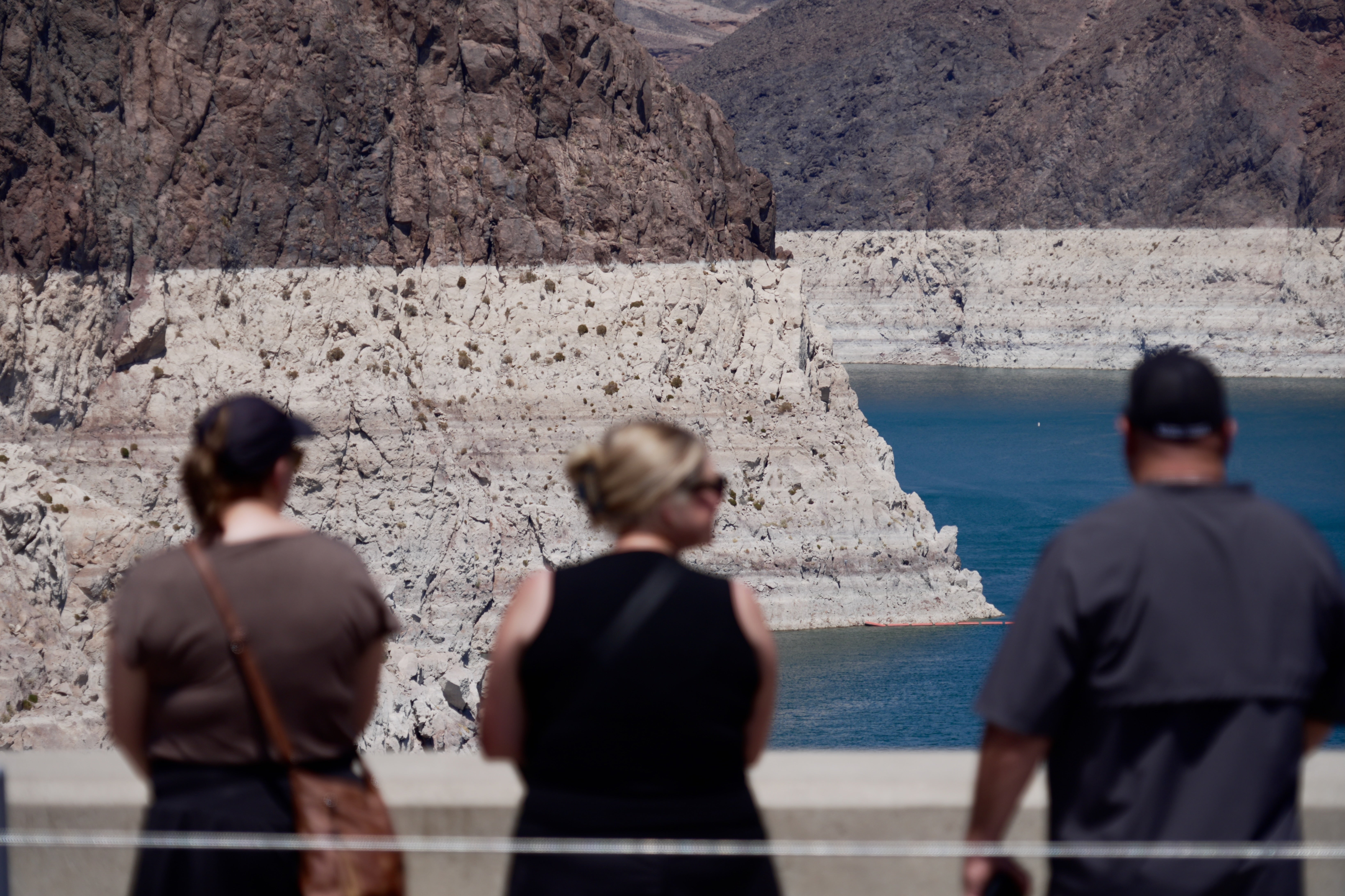 Tourists on the Hoover Dam look out at the bathtub ring of minerals that shows the former water levels of Lake Mead near Boulder City, Nevada