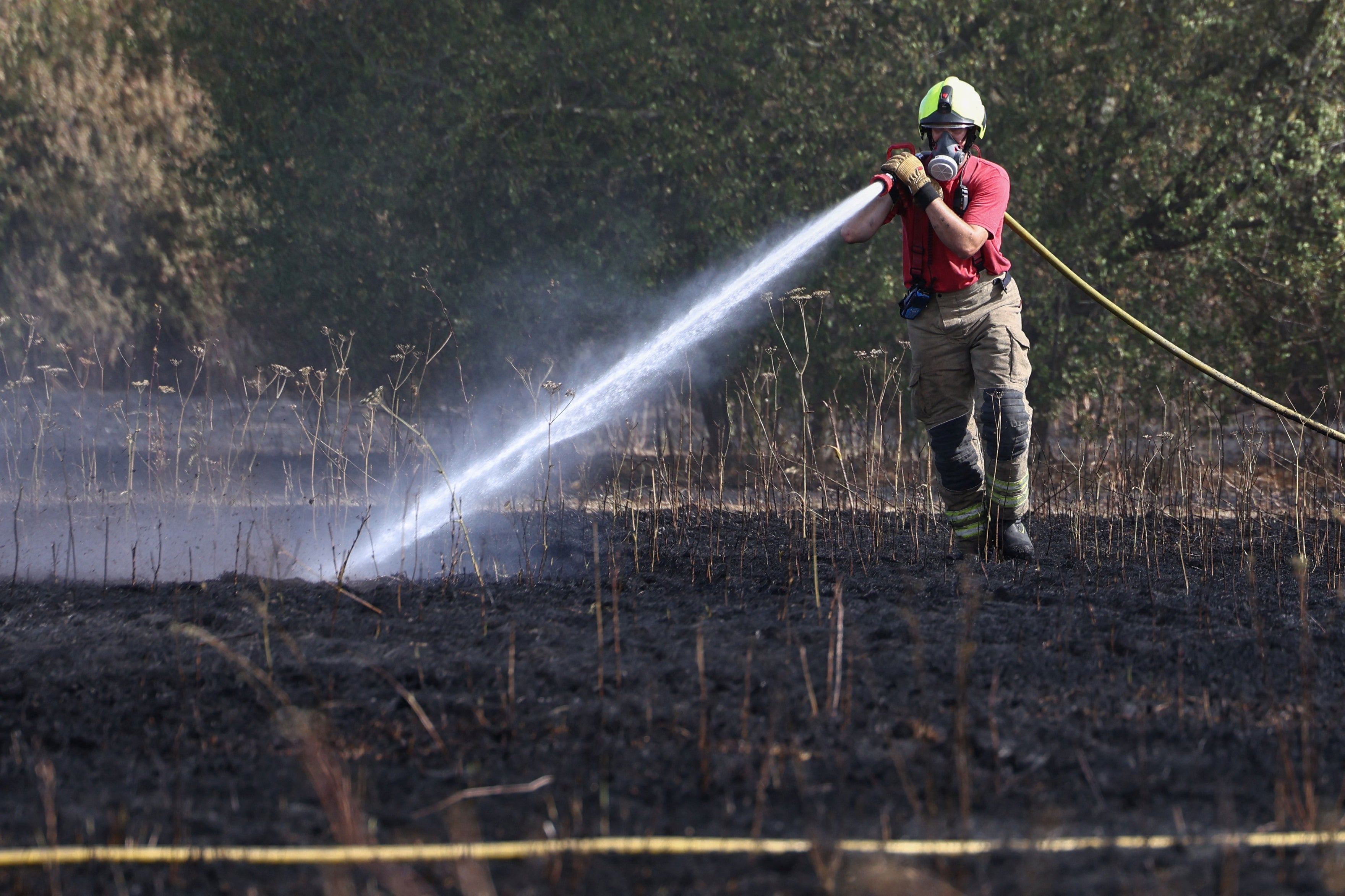 A firefighter works to contain a grass fire which started at Lake Farm Country Park in Hayes on 8 August