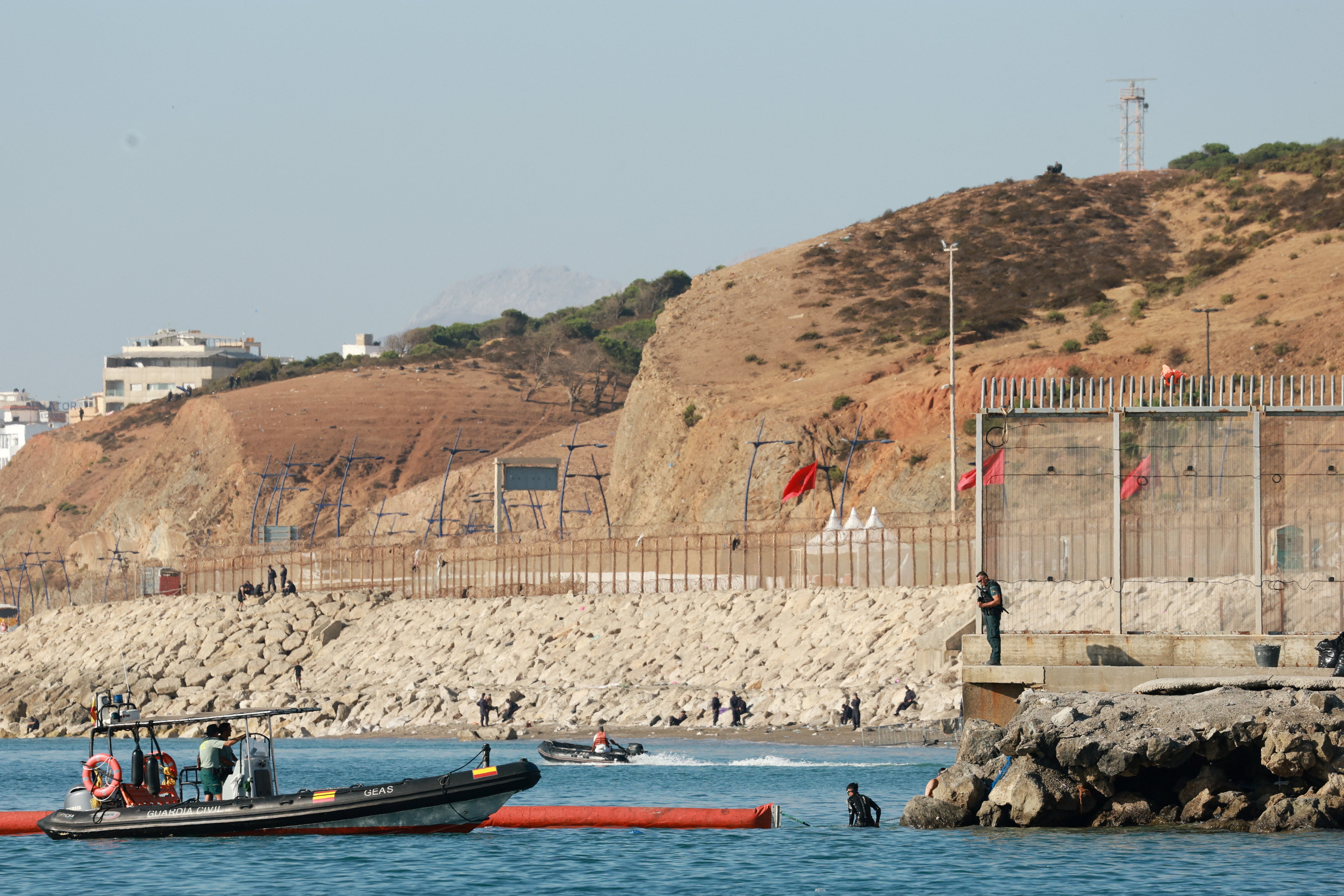 Members of the Spanish Guardia Civil patrol and conduct searches near a floating barrier off the border with Morocco
