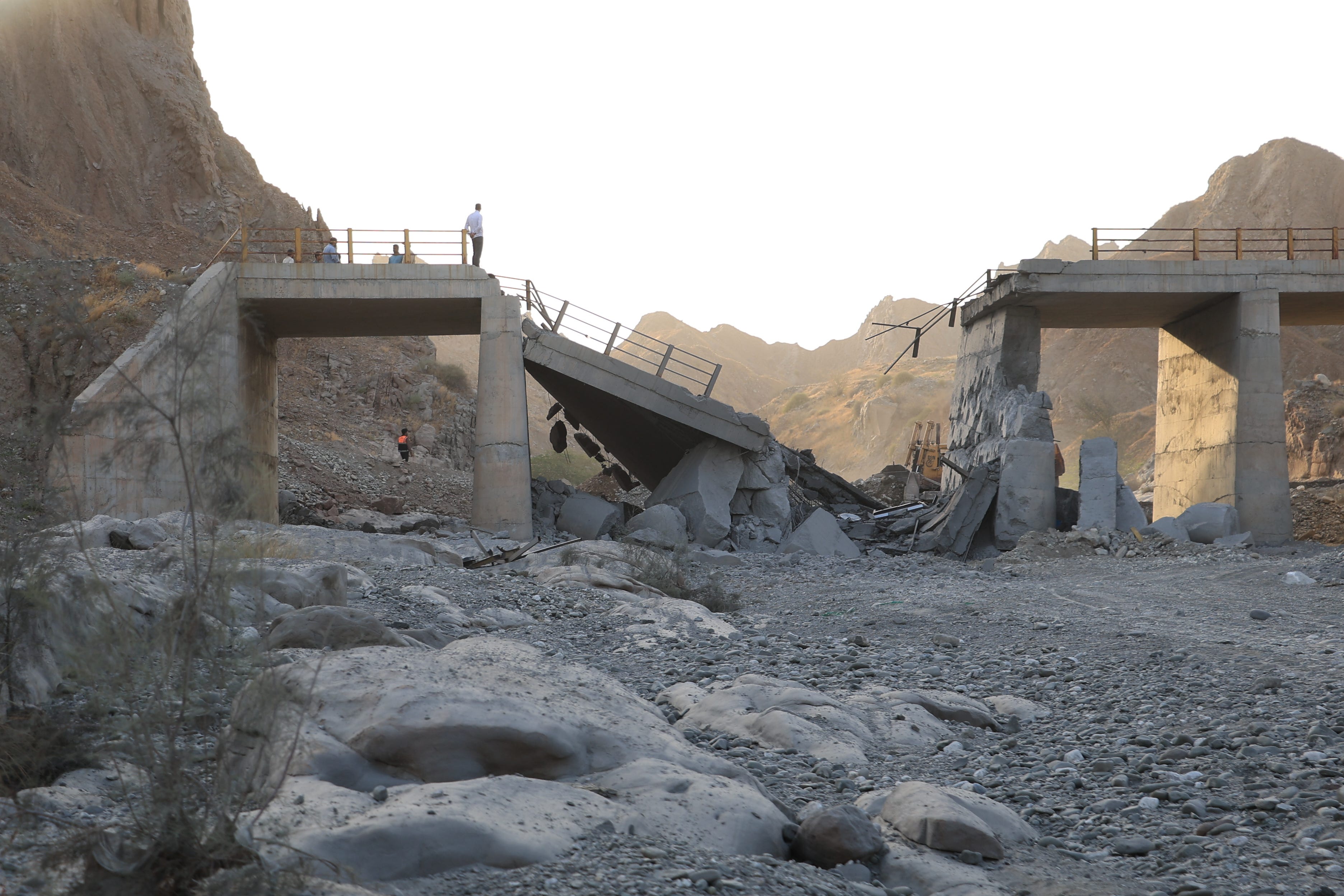 People stand on a bridge destroyed after a strike in Hormozgan province, southern Iran