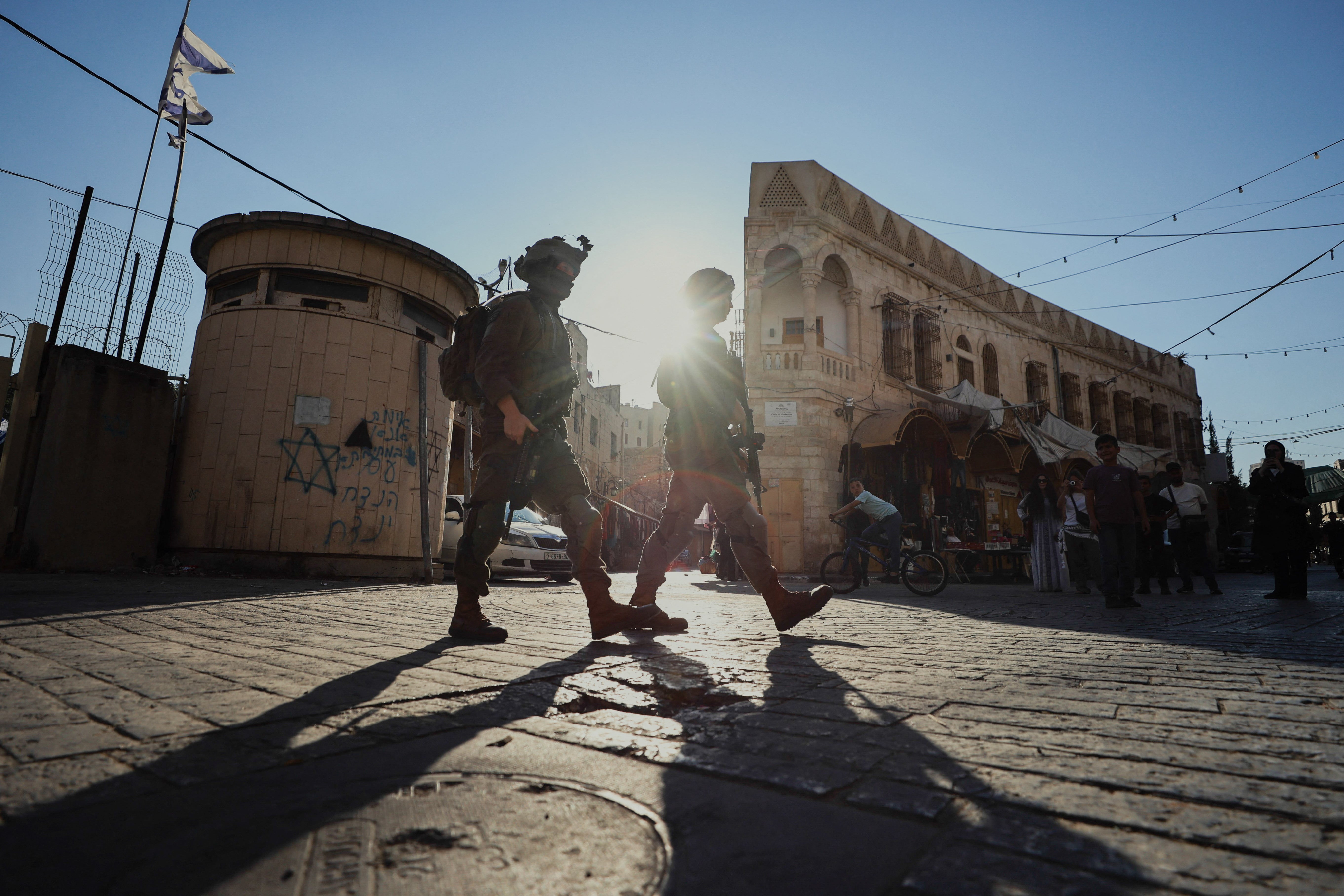 Armed Israeli soldiers patrol a street in the Old City of Hebron, in the occupied West Bank, on 8 August 2026