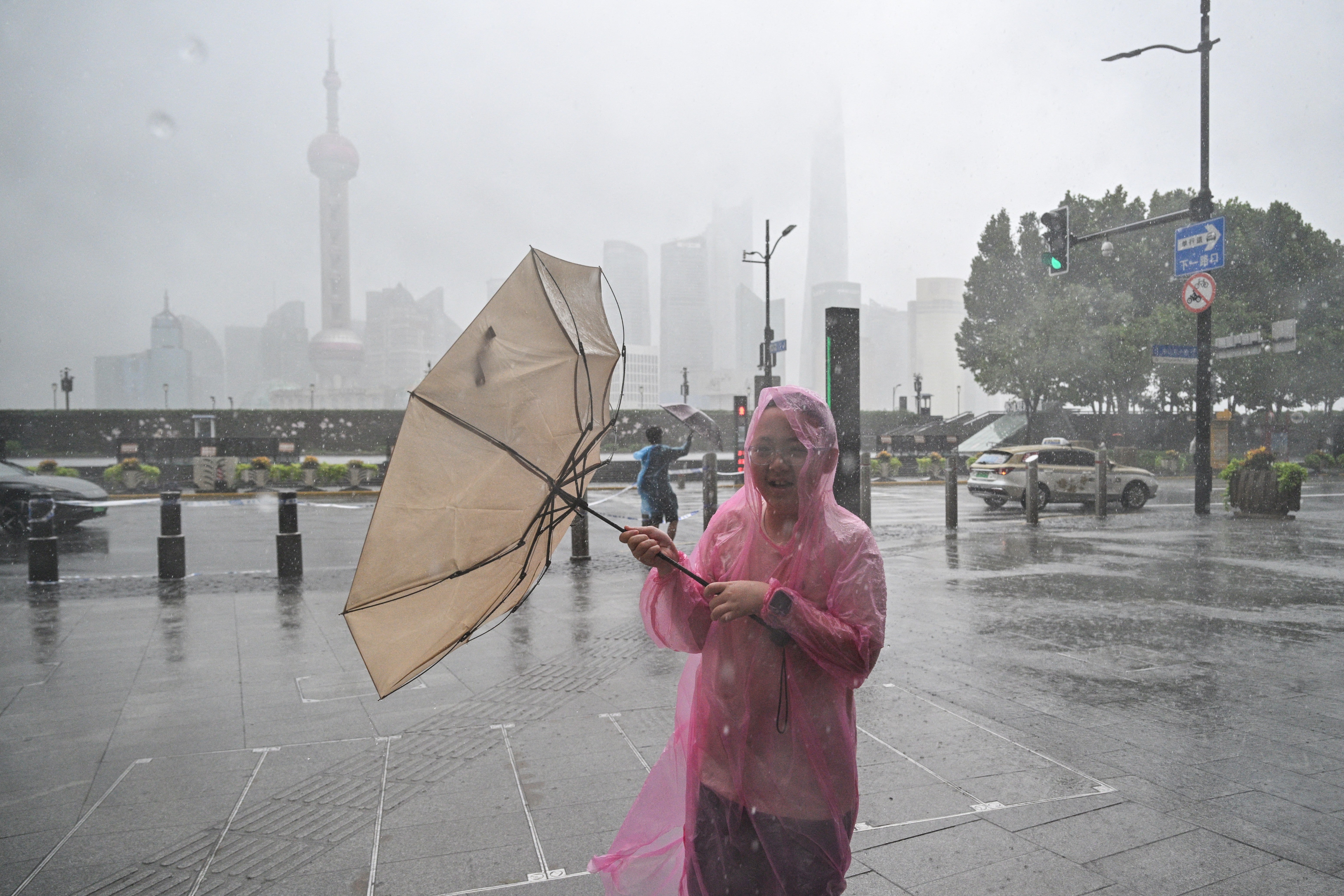 People use umbrellas to shelter from the rain as they walk on the Bund a day after Typhoon Dolphin (AFP/Getty)