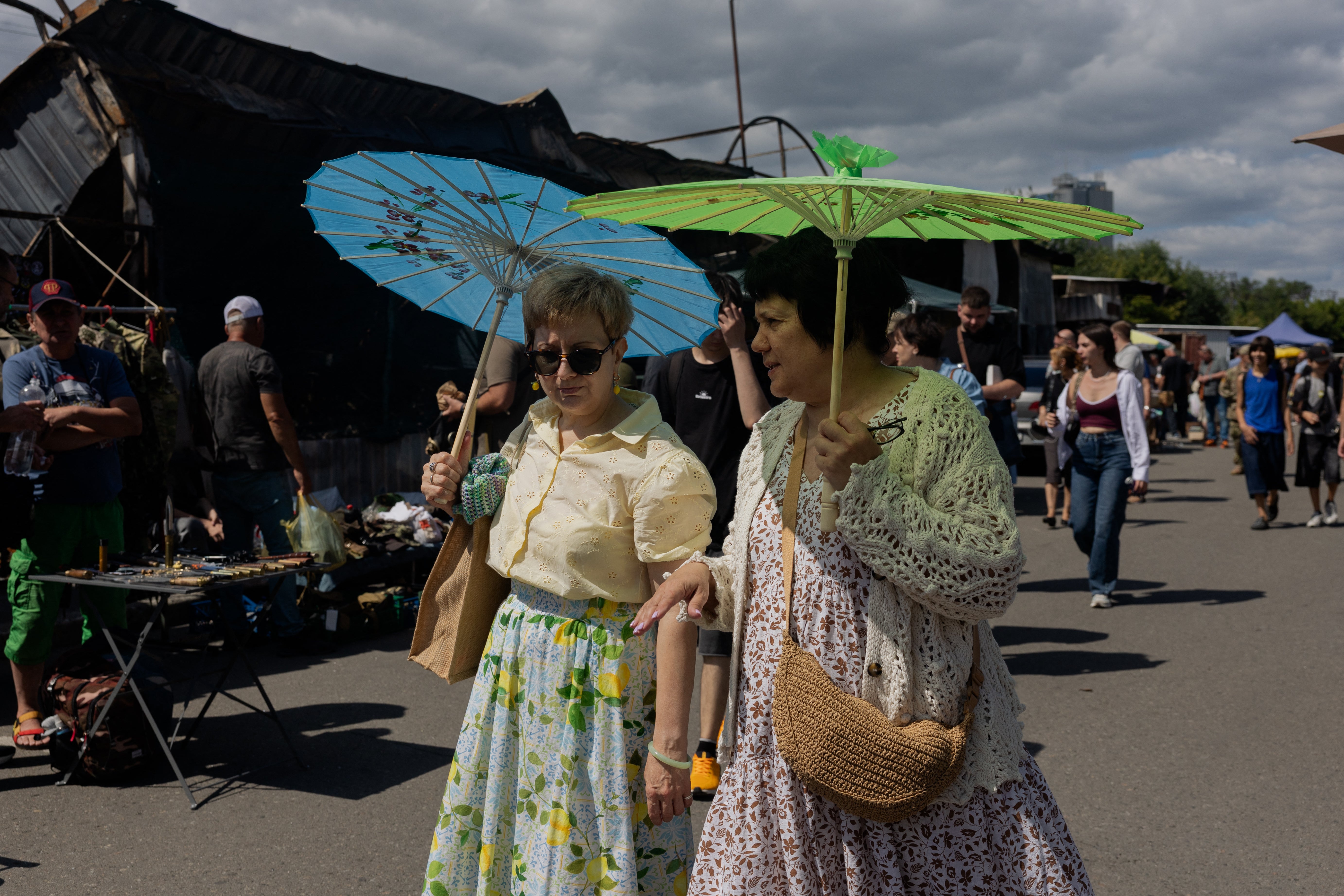 Women holding umbrellas to protect themselves from the sun walk along a damaged street market (AFP/Getty)