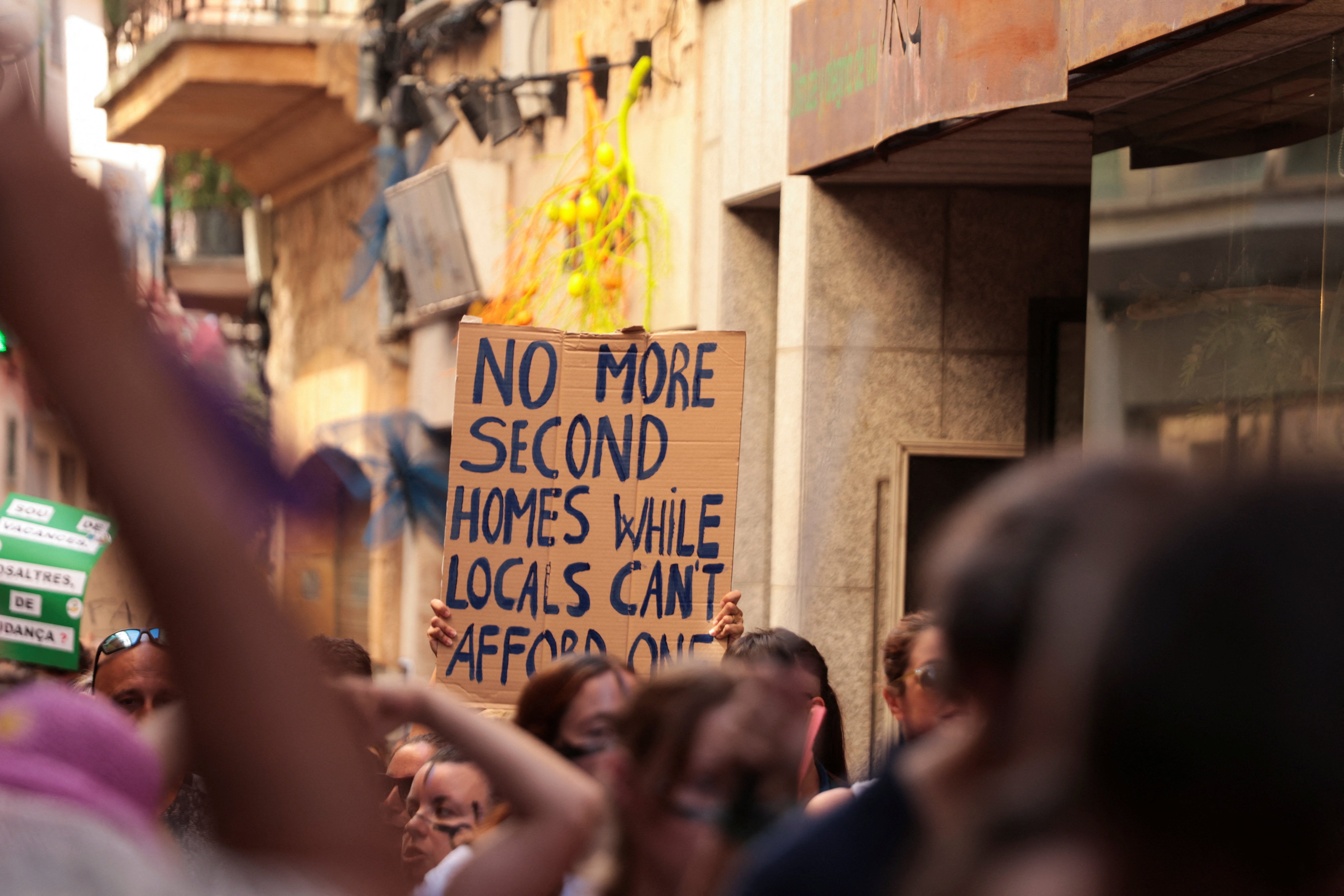 A demonstrator holds a sign during a protest against mass tourism and gentrification in the Balearic Islands, in Soller, Mallorca, Spain
