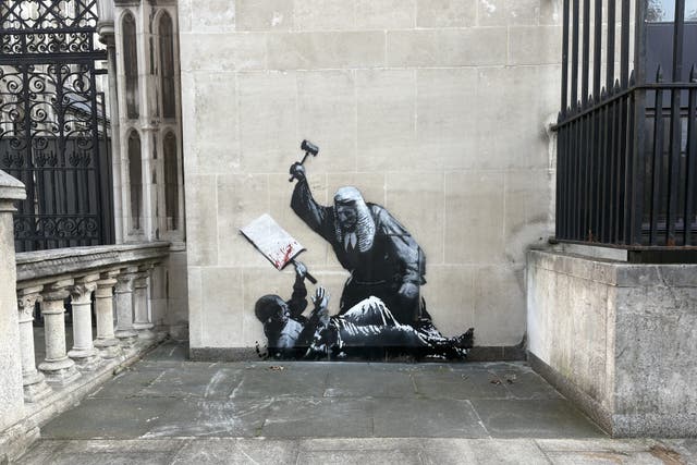 An artwork by Banksy at the Royal Courts of Justice in London which shows a judge attacking a protester with a gave